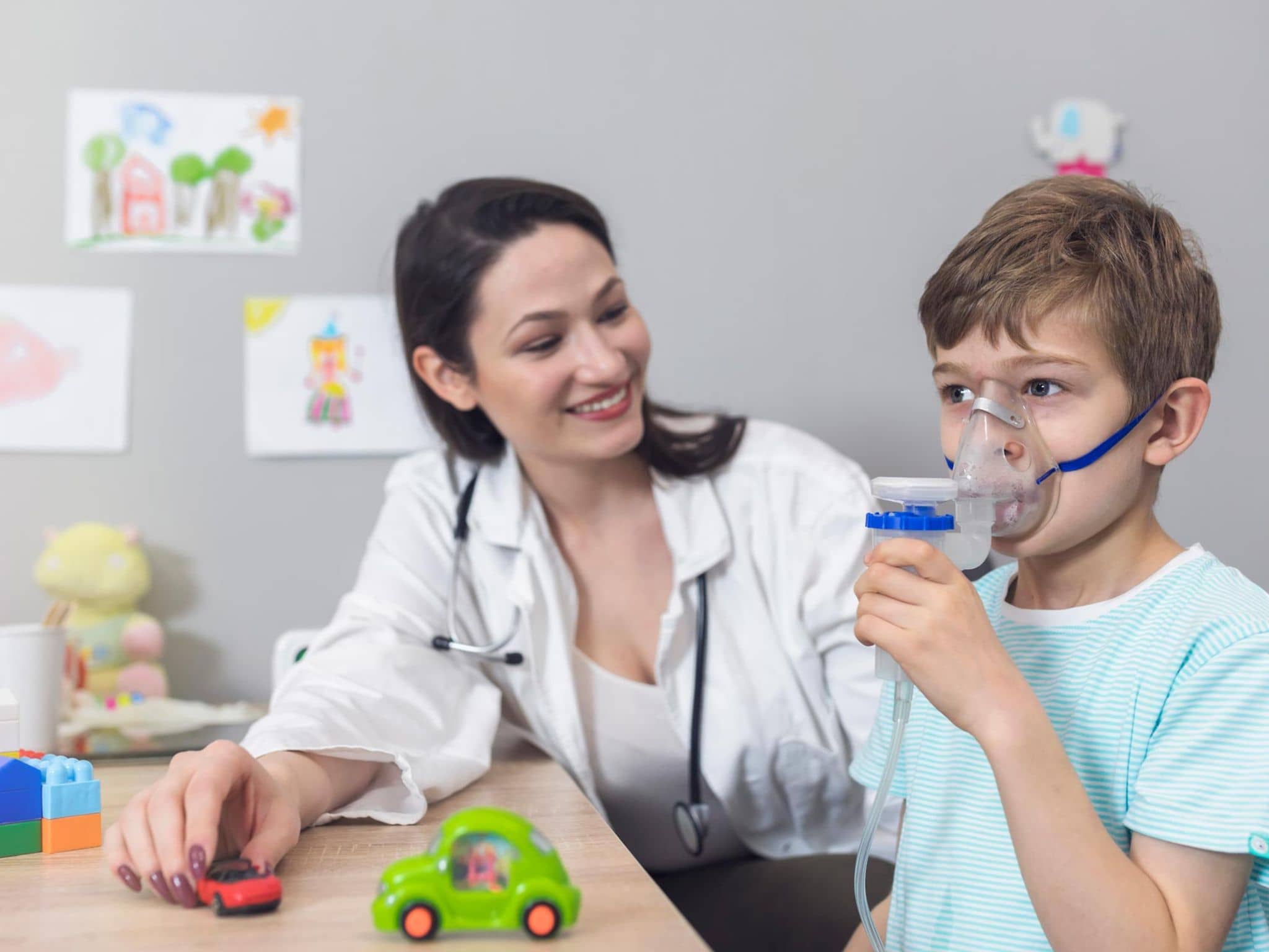 DMP: Ärztin erklärt einem kleinen Jungen die Nutzung eines Asthma-Inhalators.