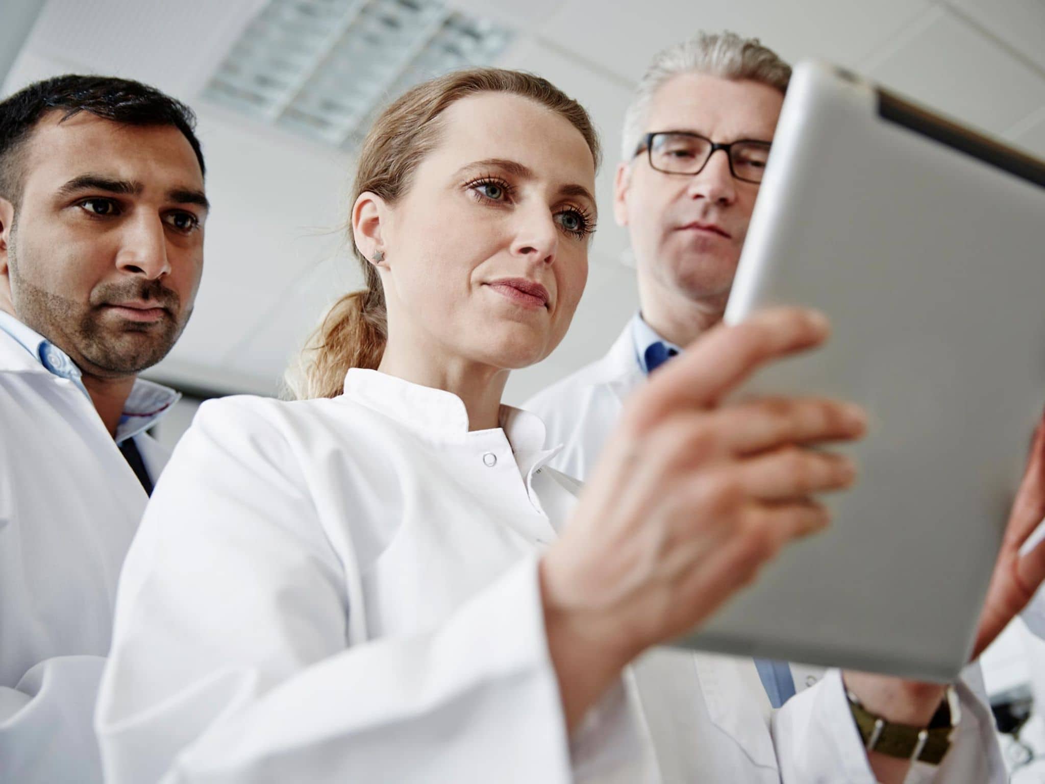 Innovationsfonds: Team von Wissenschaftlern schaut gemeinsam auf ein digitales Tablet.