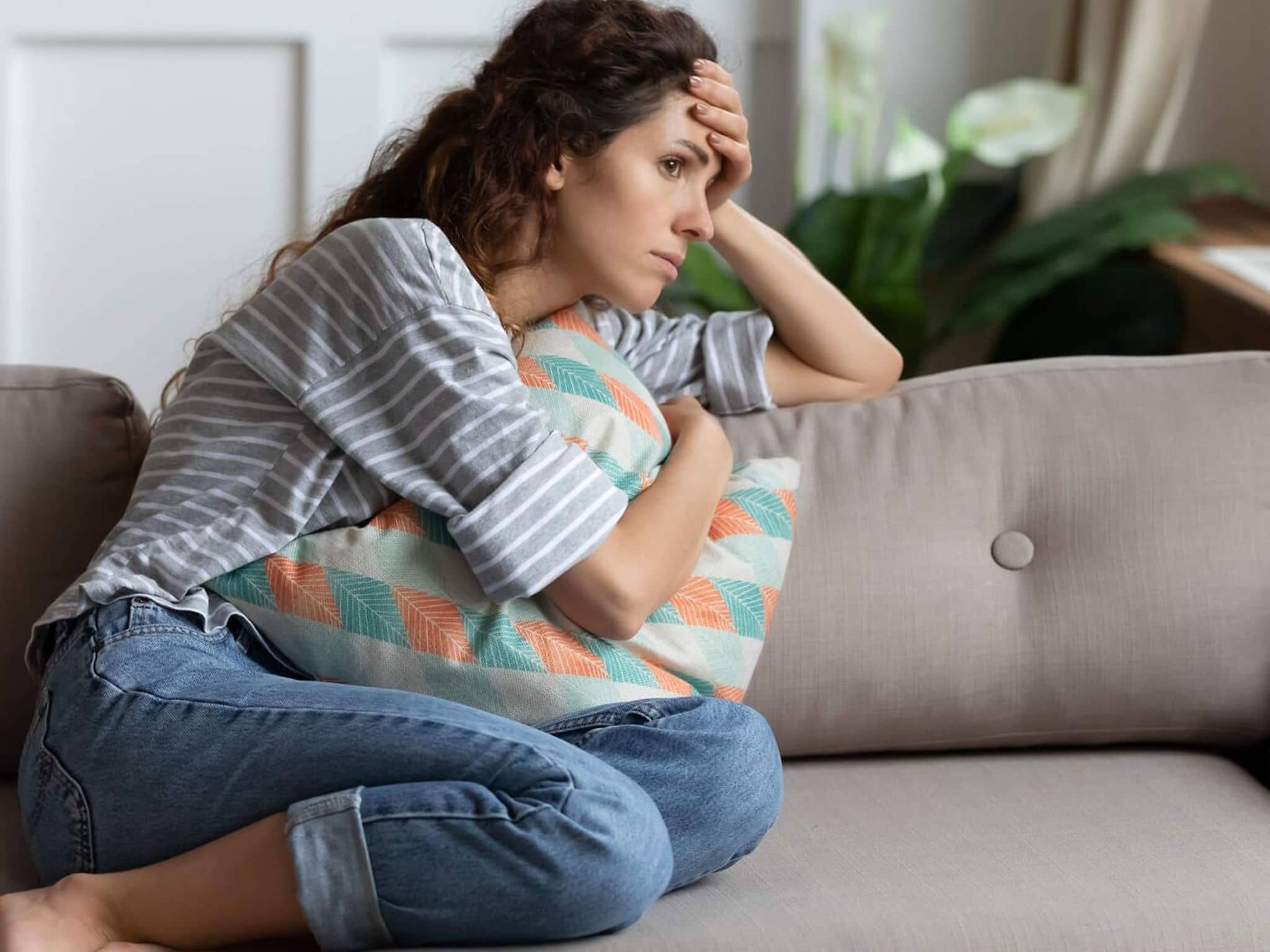 Frau sitzt erschöpft auf dem Sofa und starrt ins Leere