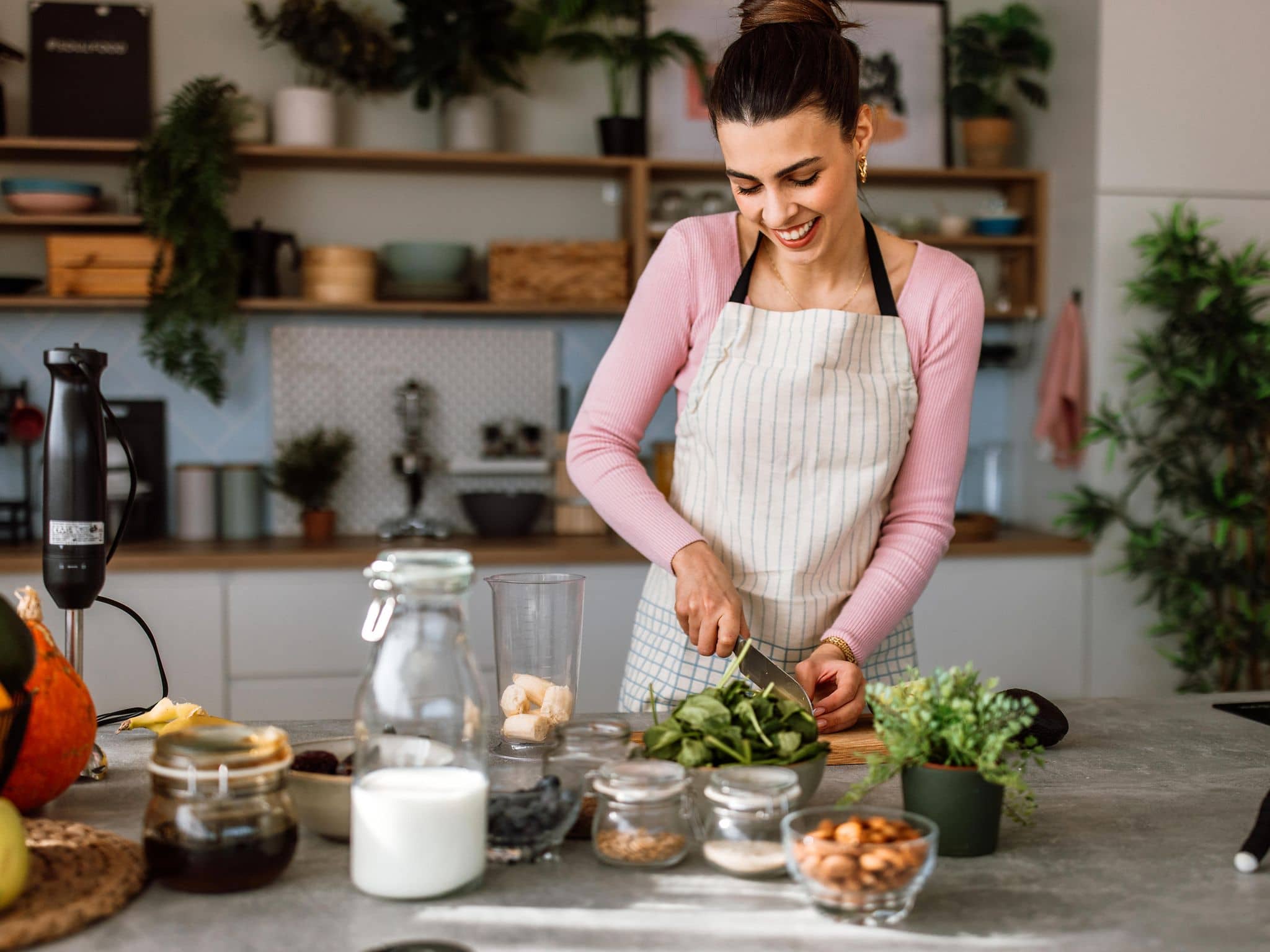 Vitamin E: Eine Frau steht in der Küche und bereitet sich eine gesunde Mahlzeit zu