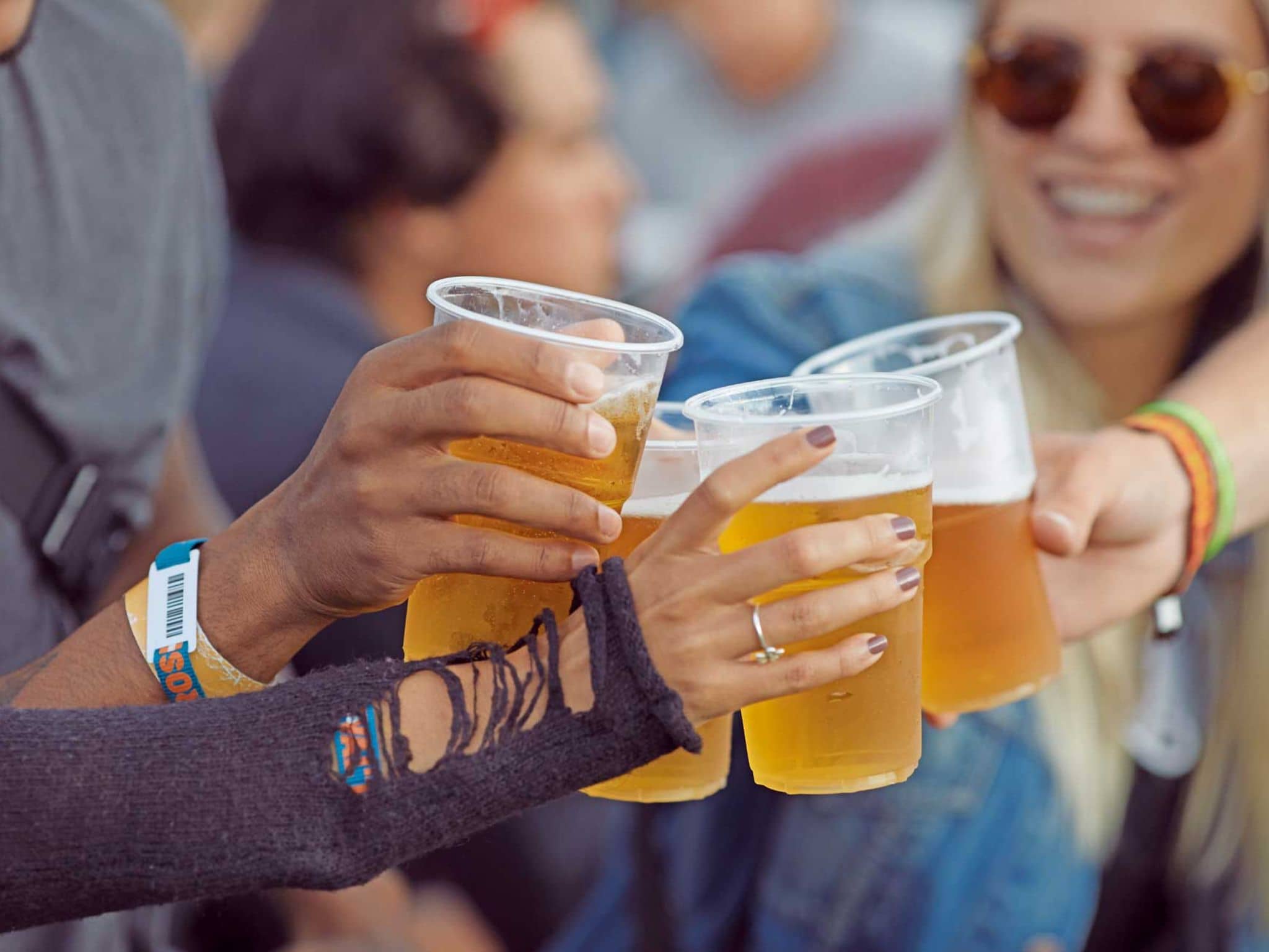 Nahaufnahme von Händen, die mit Bechern voll Bier anstoßen