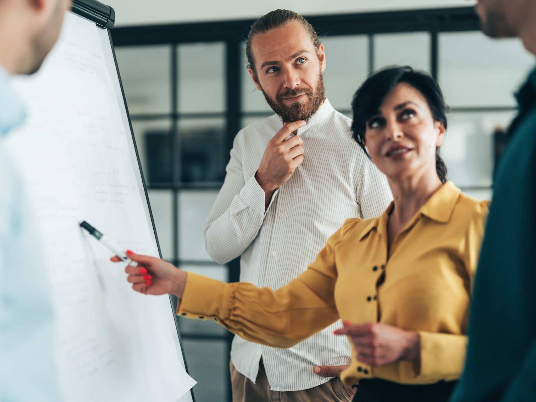 Frau vor Flipchart in Diskussion mit Kollegen