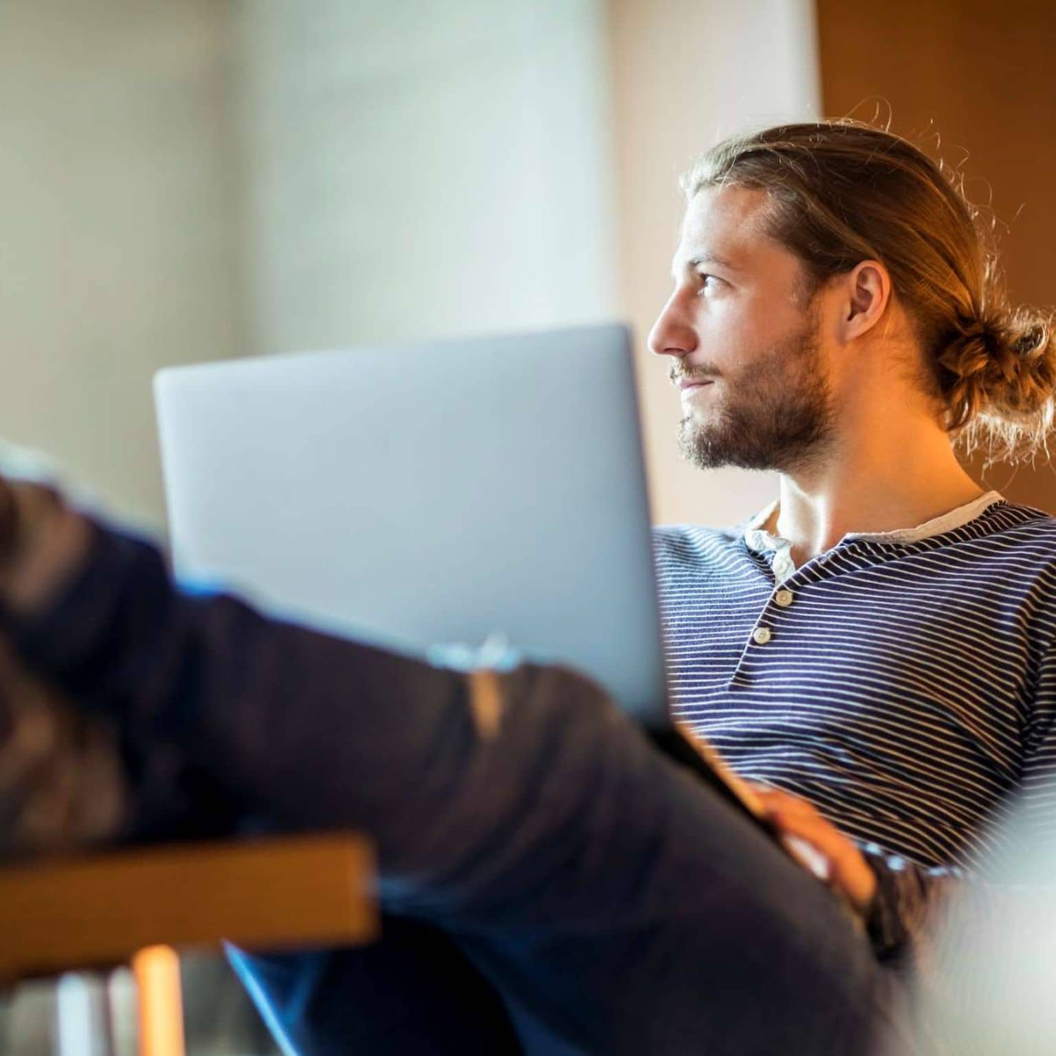 Work-Live-Balance: Mann sitzt in entspannter Pose mit Laptop auf dem Schoß