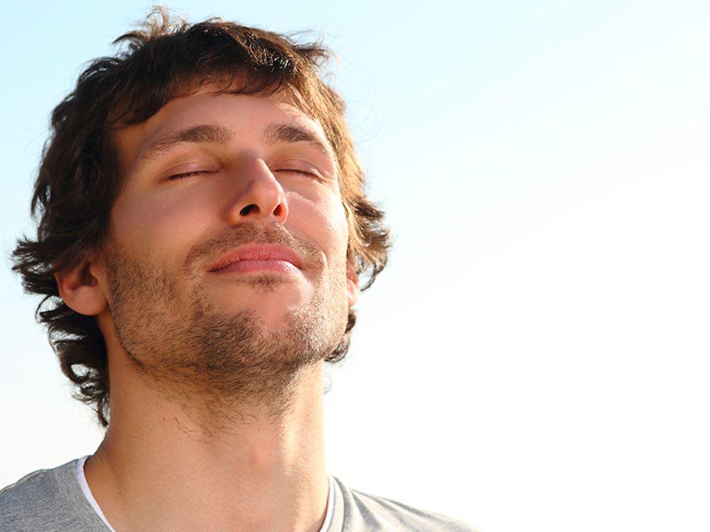 Atemtechnik: Ein Mann atmet mit geschlossenen Augen tief ein