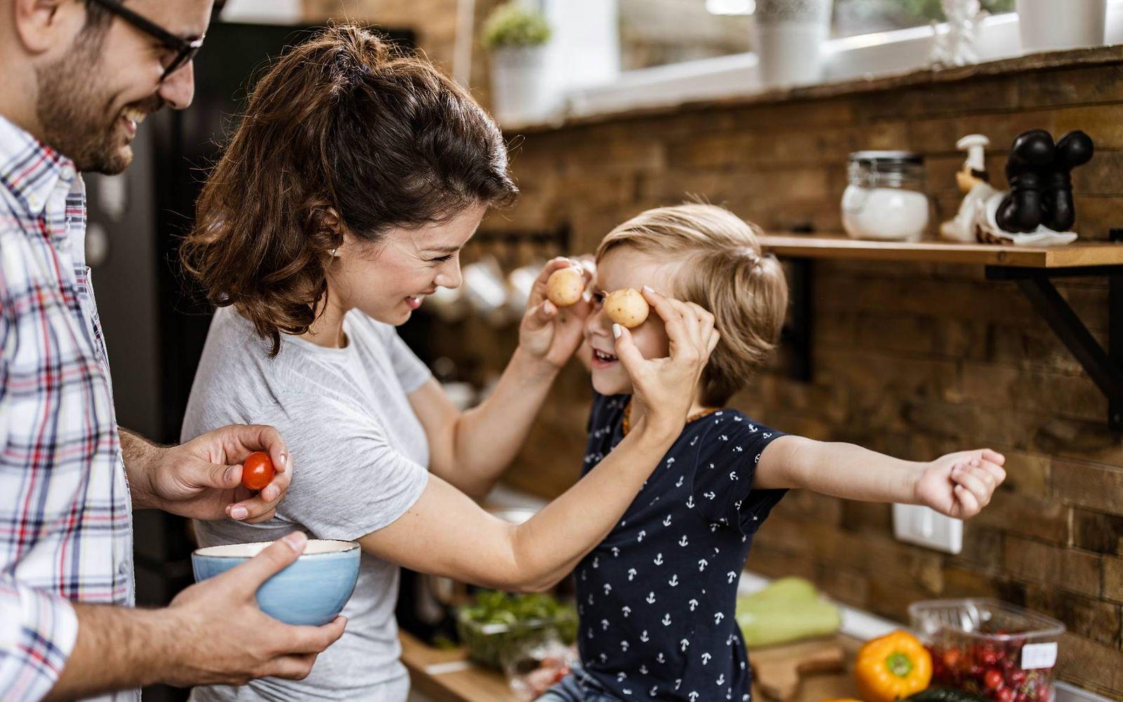 Resistente Stärke: Mutter und Vater spielen mit ihrem kleinen Sohn in der Küche