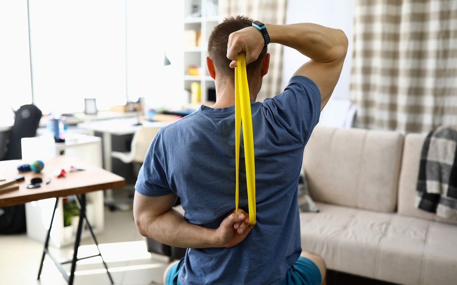 Bild: Online-Seminar Rückengesundheit: Mann benutzt gelbes Theraband hinter seinem Rücken.
