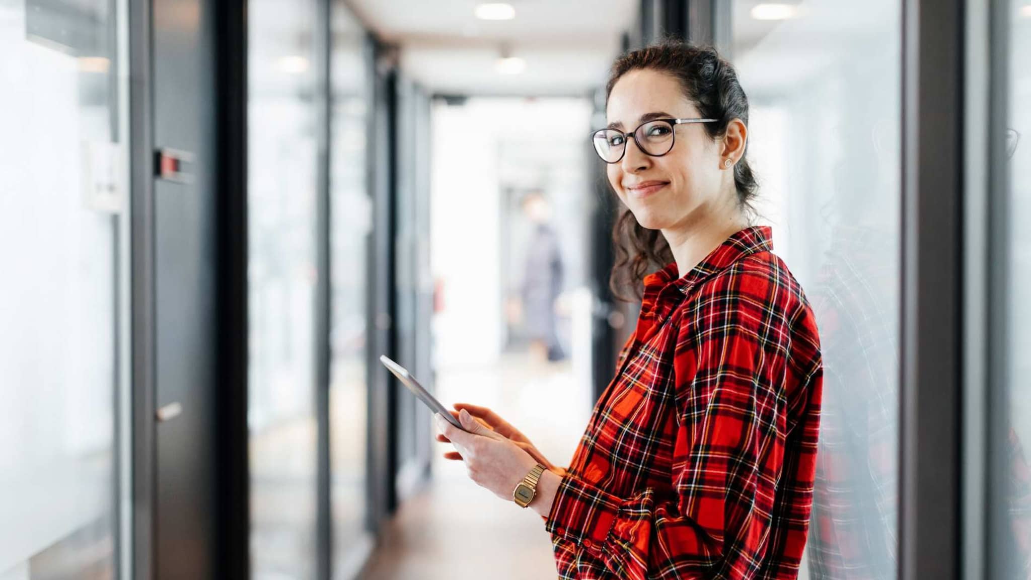 Bild: Frau mit Tablet steht in einem Gang.