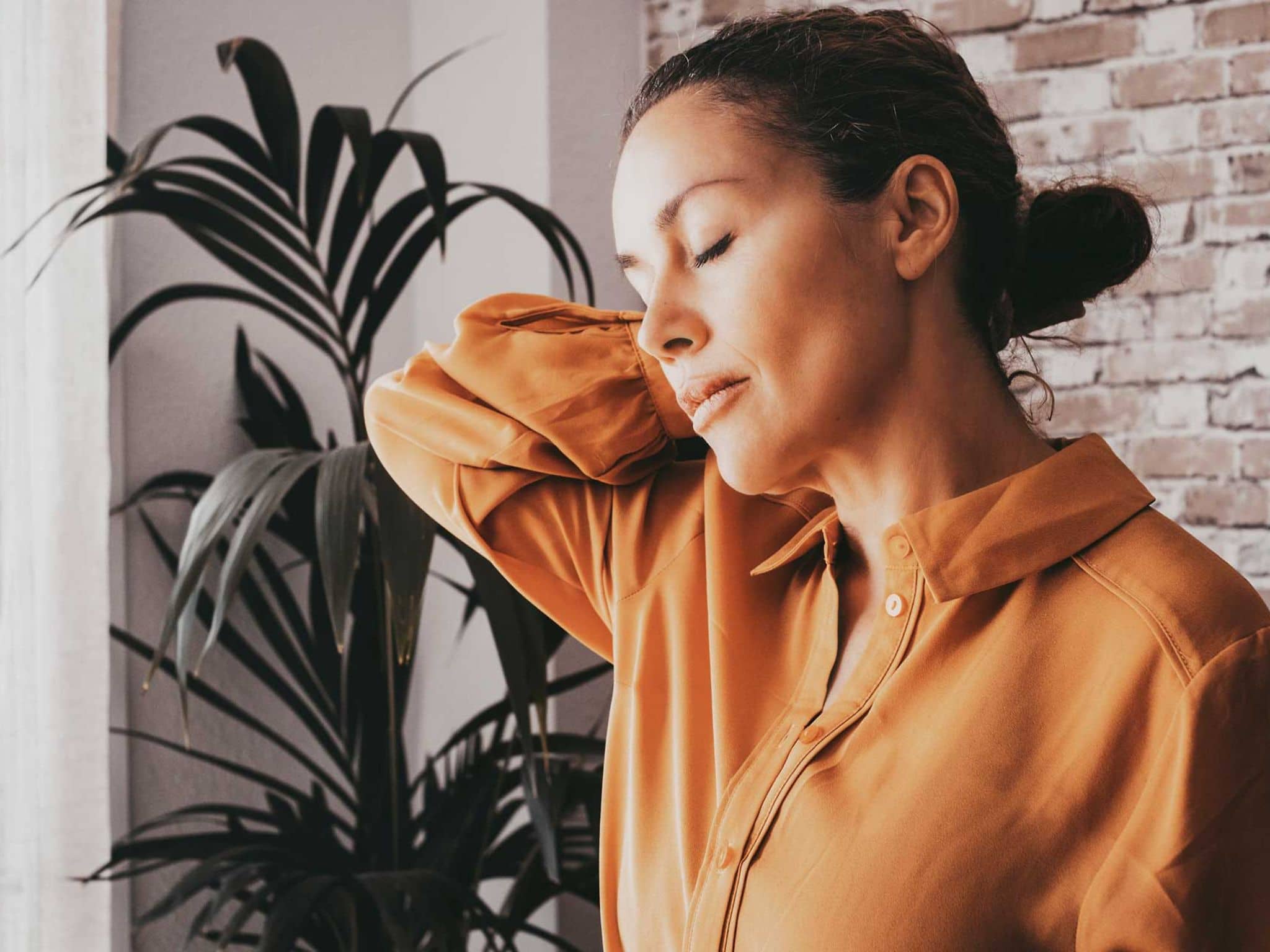 Symbolbild Zeitumstellung: Frau fasst sich erschöpft in den Nacken