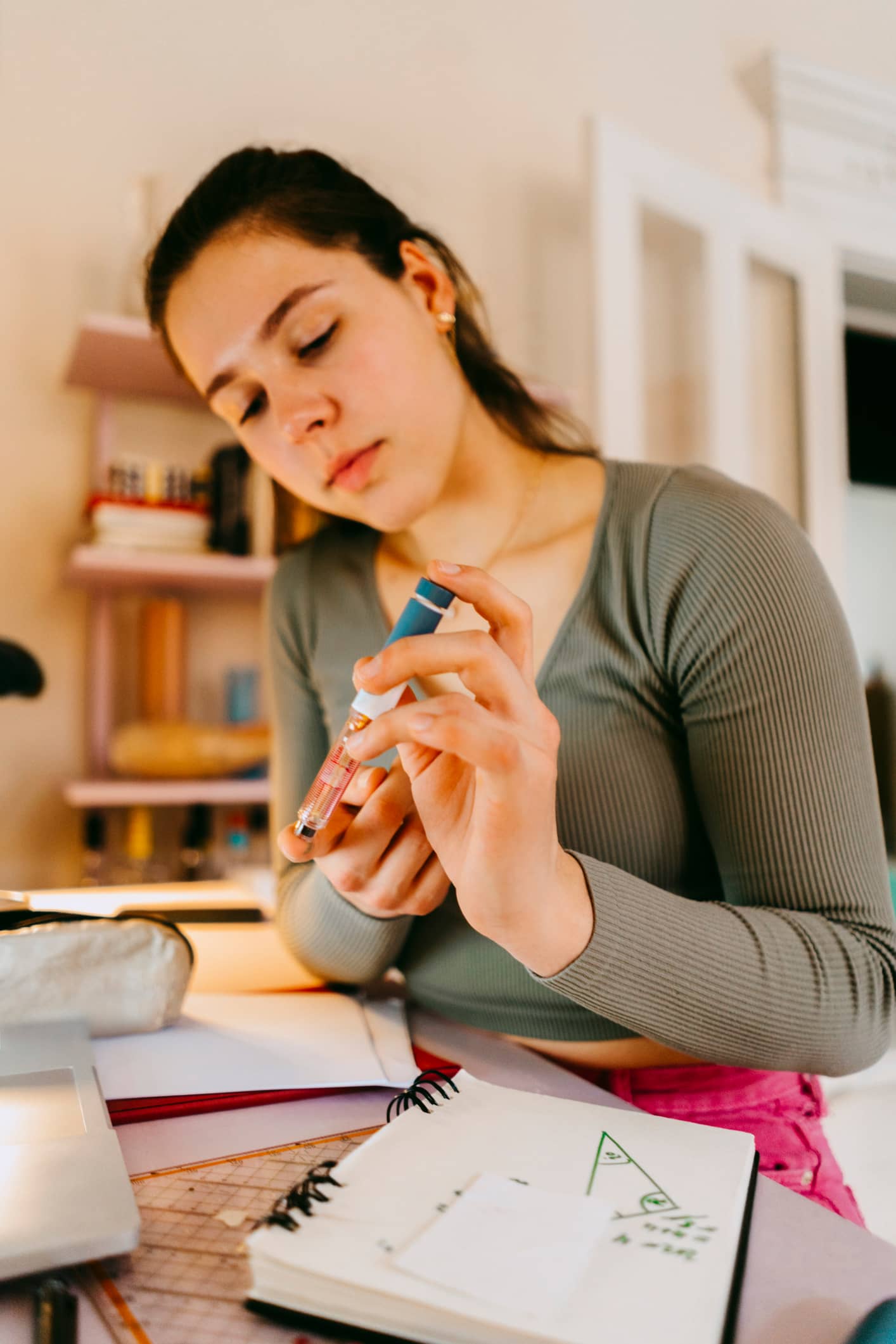 Eine junge Frau mit sitzt an einem Schreibtisch und misst ihren Blutzuckerwert