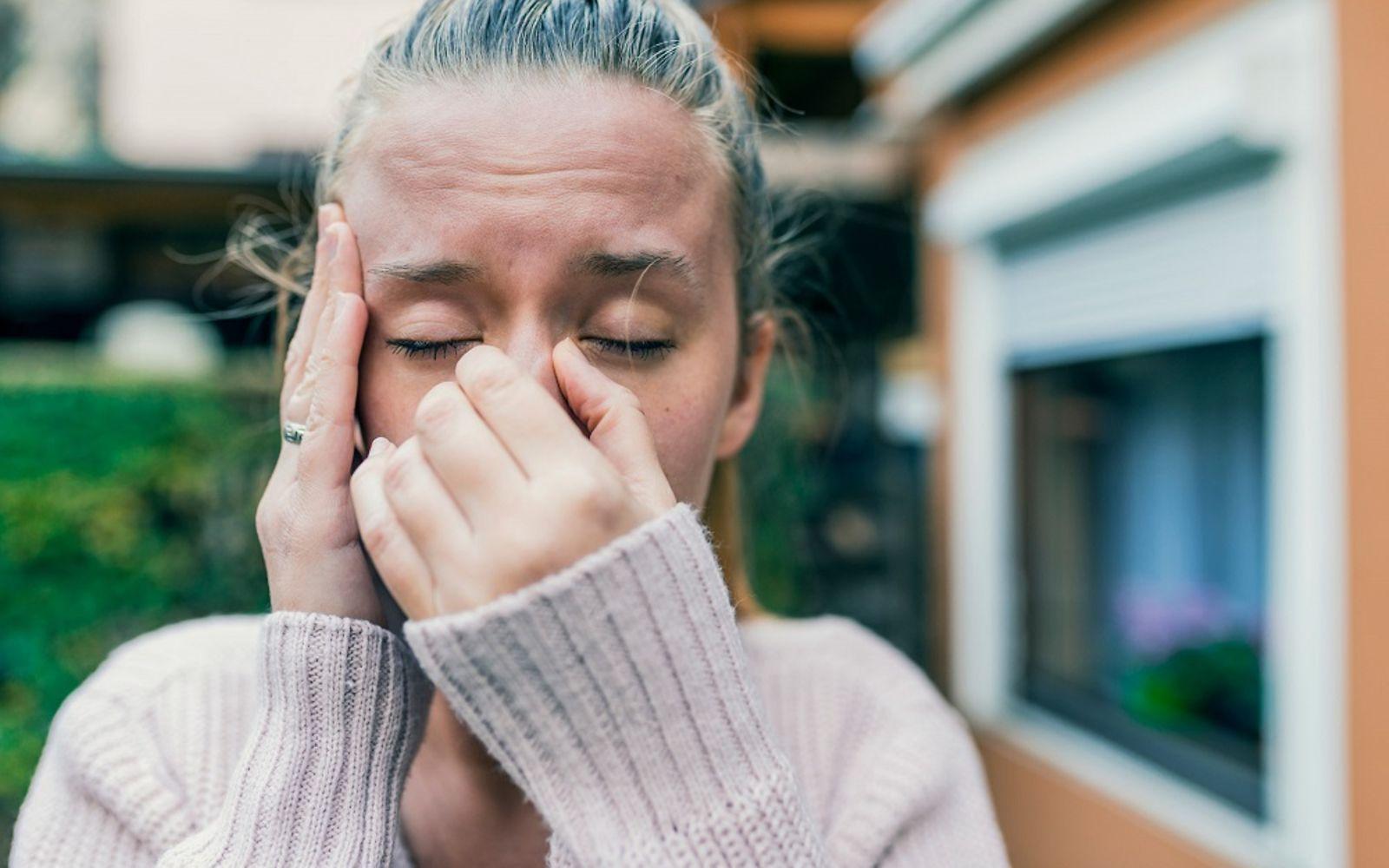 Spannungskopfschmerzen: Frau mit geschlossenen Augen hält die Hände an Schläfe und Nase.