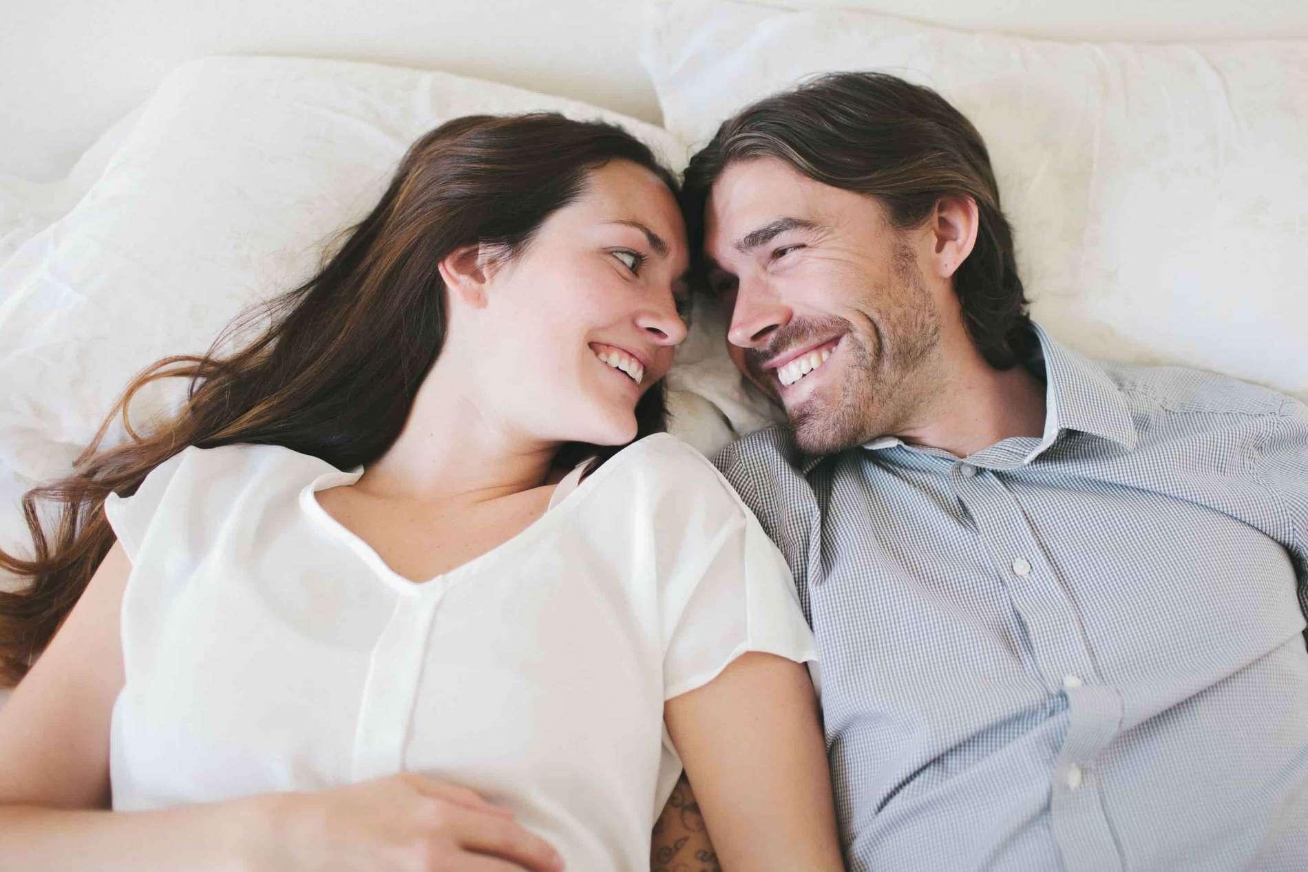Check Up 35: Mann und Frau liegen nebeneinander im Bett und lachen sich an.