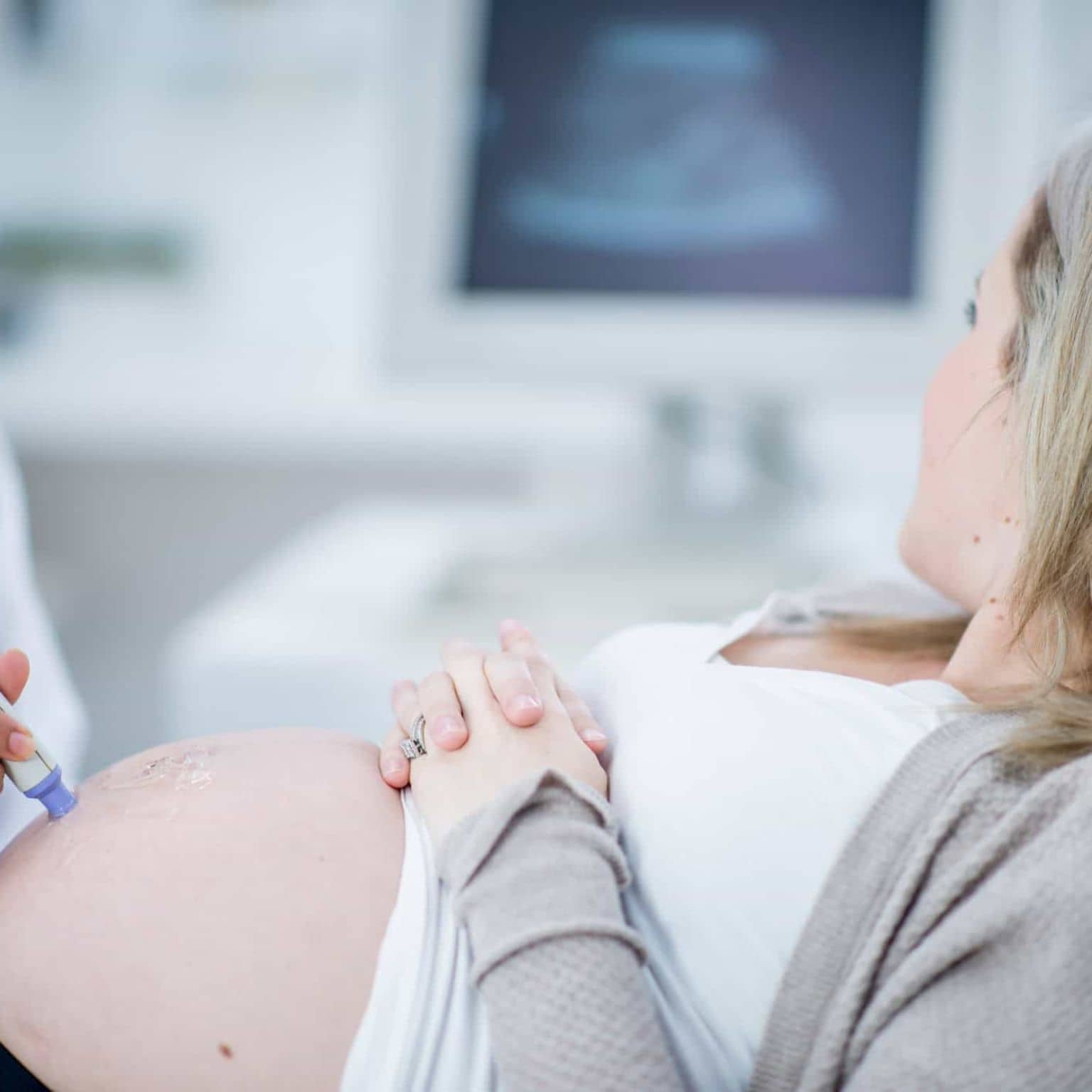 Vorsorgeuntersuchungen für Schwangere: Schwangere und Ärztin betrachten Monitor während einer Ultraschalluntersuchung.