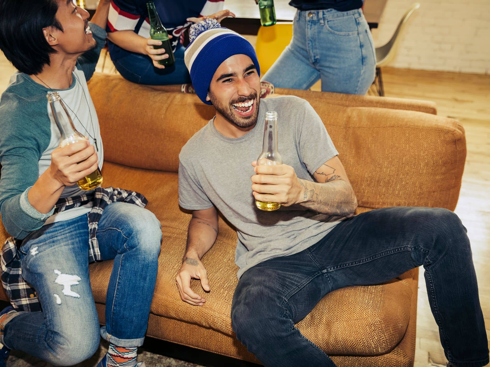 Zwei Männer sitzen auf einem Sofa, trinken Alkohol und haben Spaß