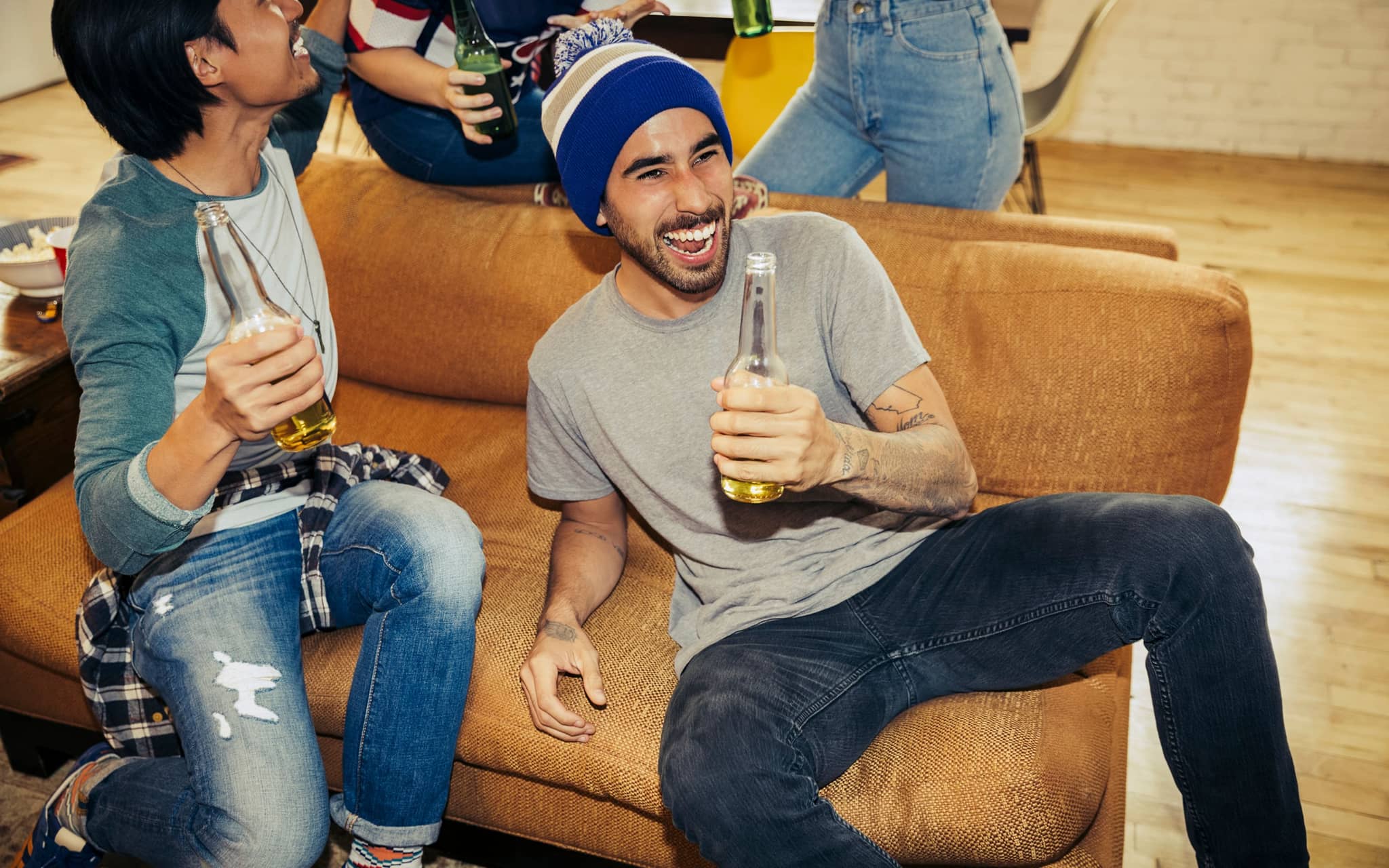 Zwei Männer sitzen auf einem Sofa, trinken Alkohol und haben Spaß