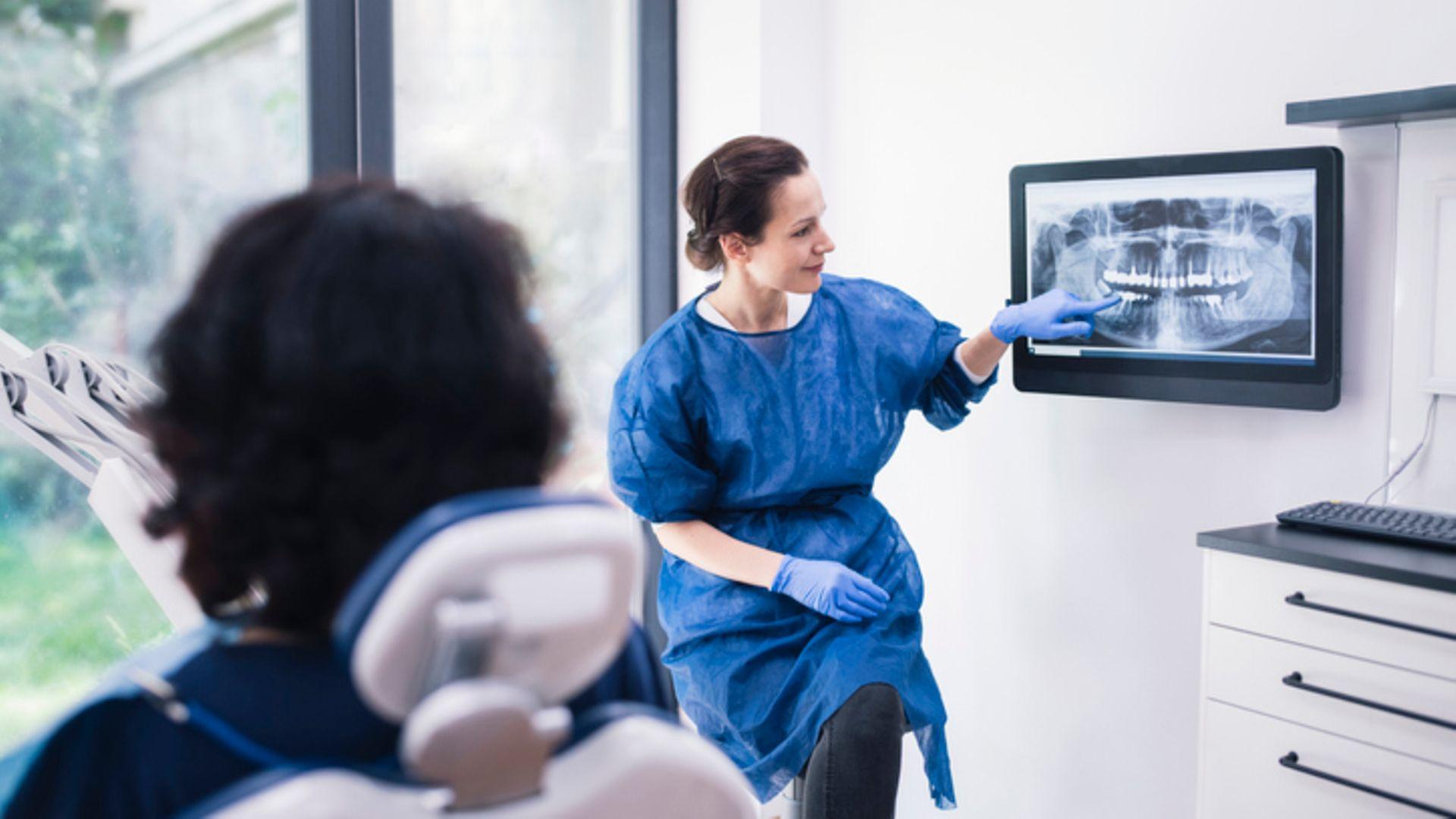 Parodontitis – was macht anfällig: Ärztin erklärt dem Patienten das Röntgenbild