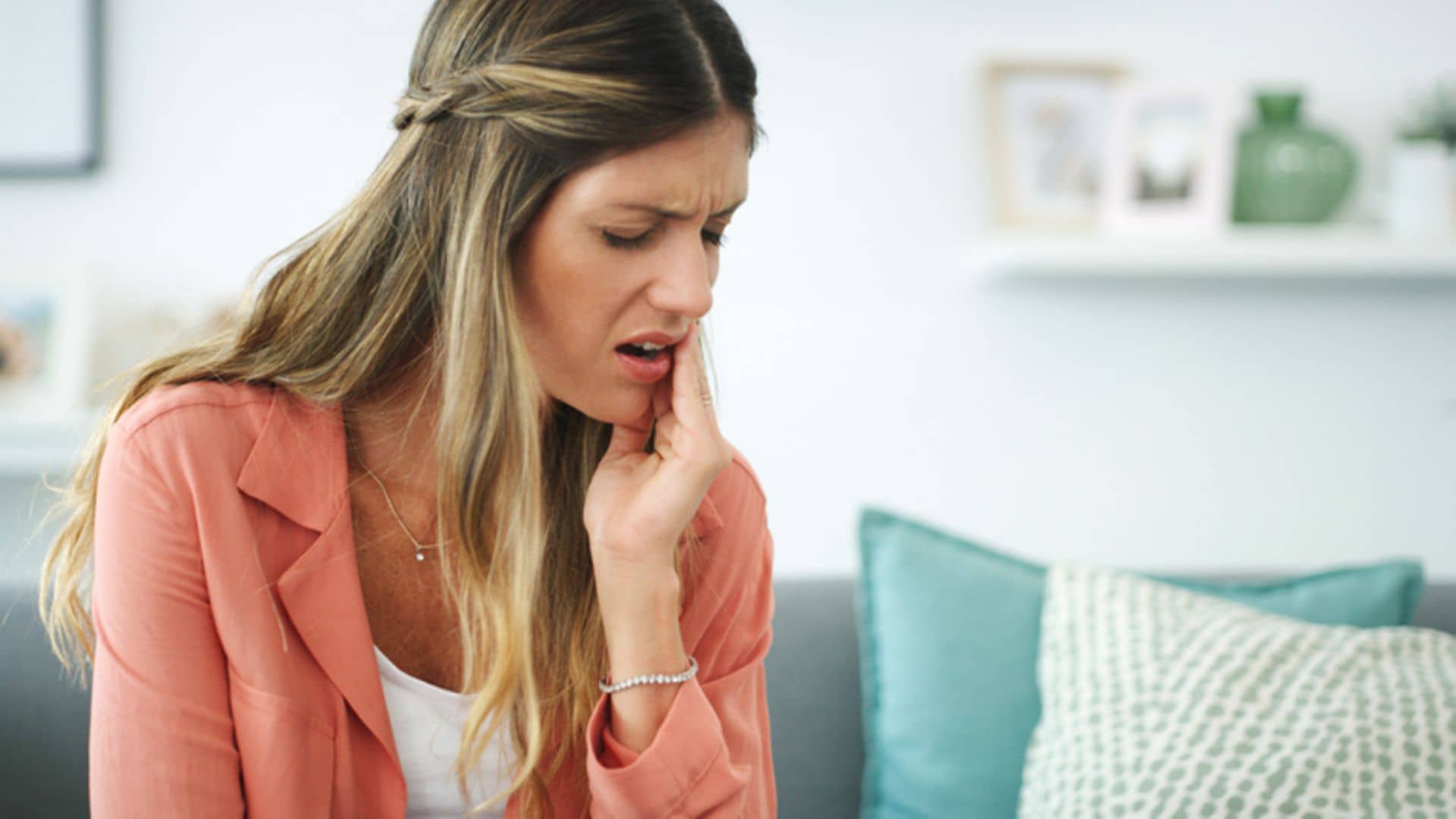 Warum wird eine Parodontitis chronisch?: Frau fasst sich an die Wange