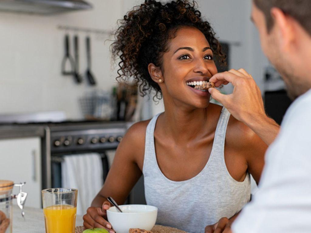 Ernährung und Parodontitis: Junges Pärchen sitzt in der Küche und frühstückt gemeinsam.