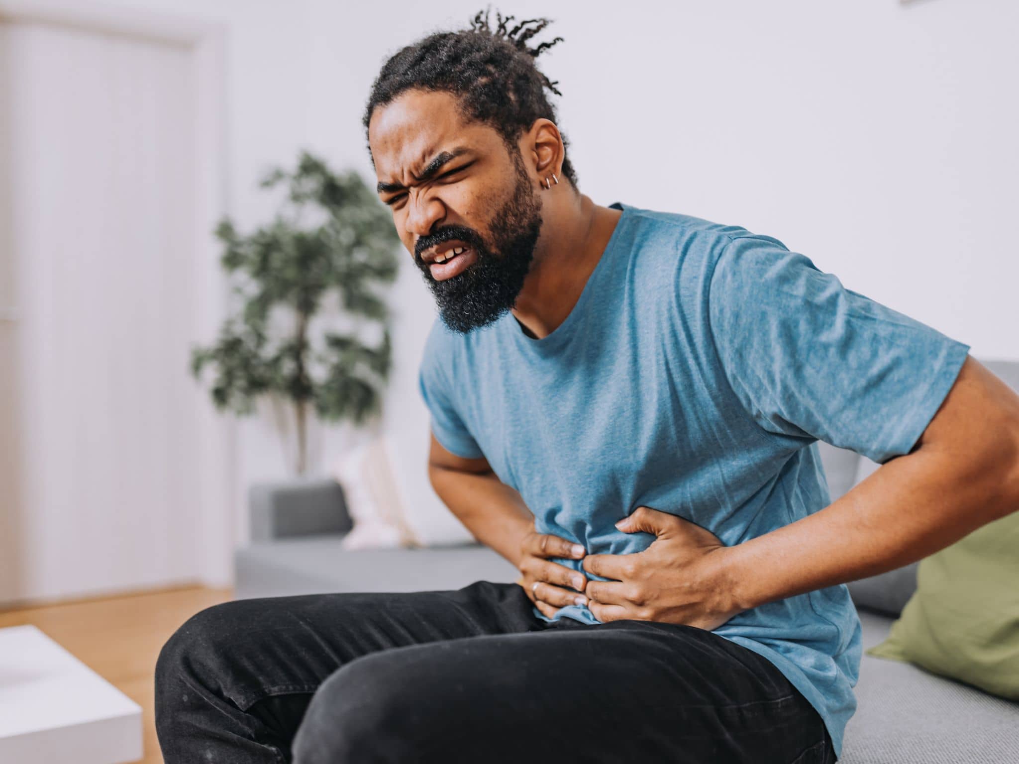 Hodenschmerzen: Ein Mann mittleren Alters hält sich den Bauch, da er Schmerzen hat