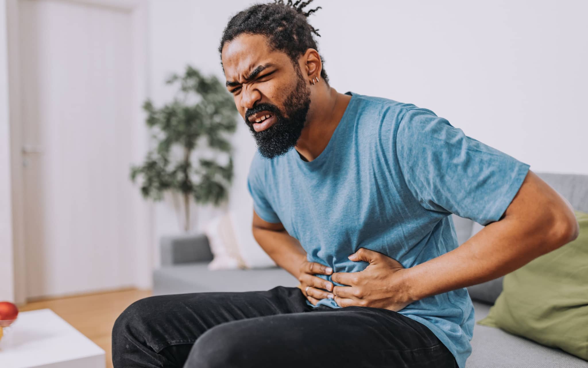 Hodenschmerzen: Ein Mann mittleren Alters hält sich den Bauch, da er Schmerzen hat
