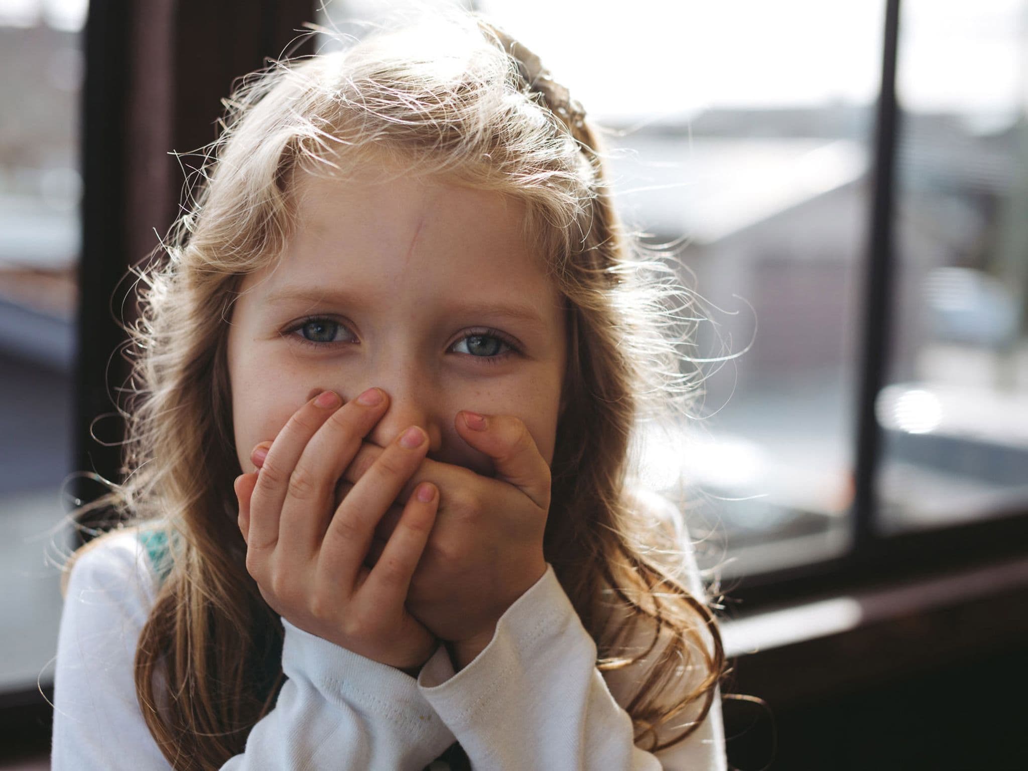 Stottertherapie: Mädchen hält sich die Hände vor den Mund.