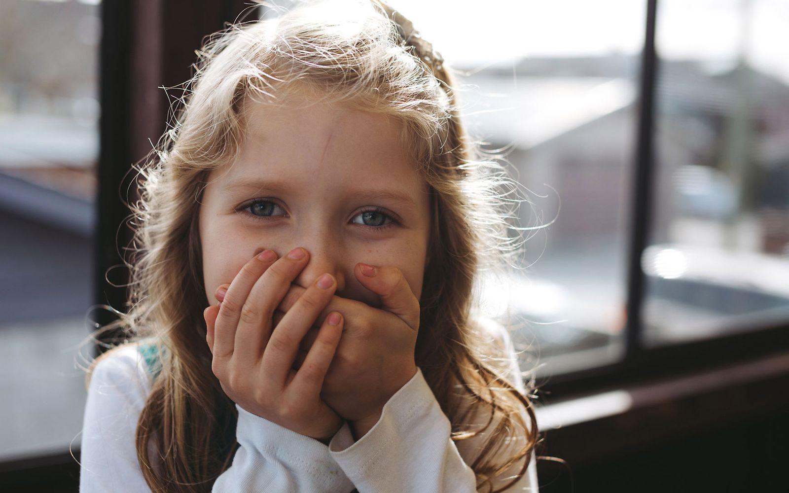 Stottertherapie: Mädchen hält sich die Hände vor den Mund.