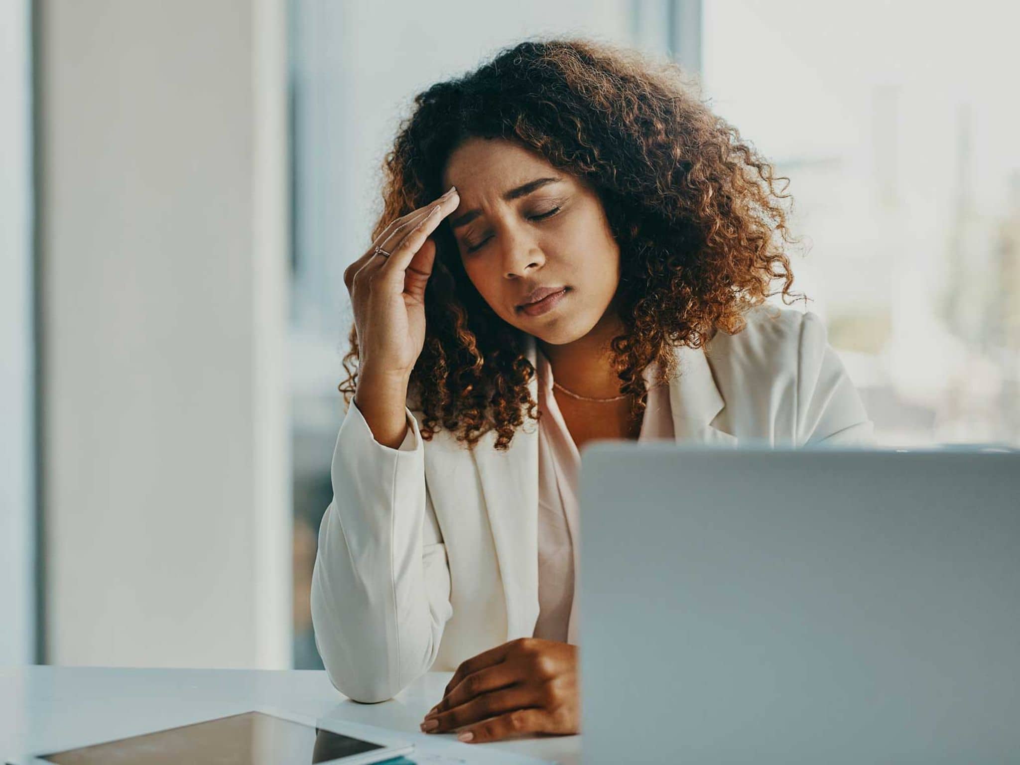 Präsentismus: Junge Frau sitzt am Schreibtisch und fühlt sich unwohl