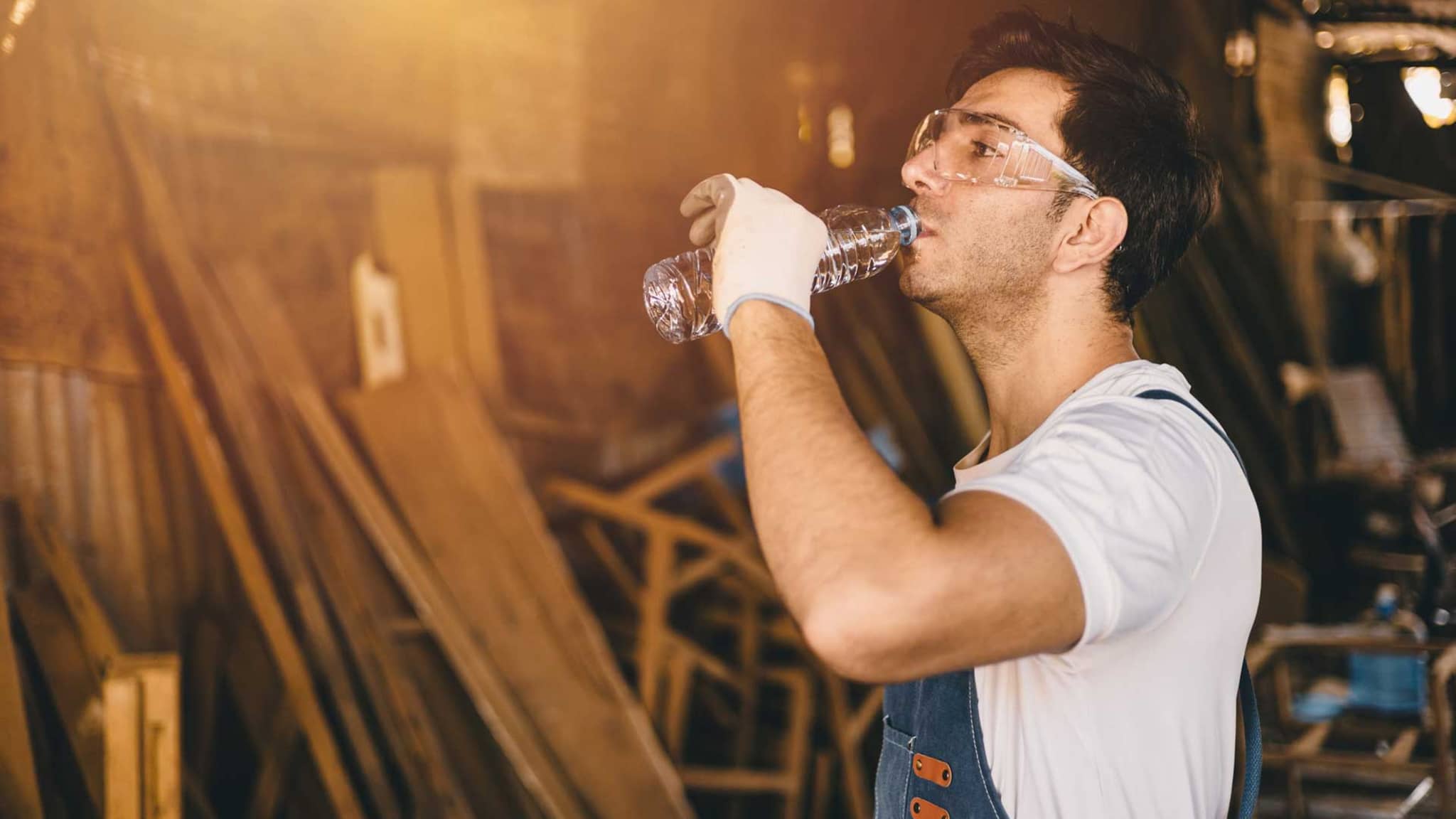 Symbolbild Hitze am Arbeitsplatz: Handwerker trinkt aus einer Flasche