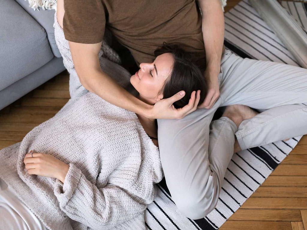 Symbolbild Stressbewältigungstraining: Frau liegt entspannt auf dem Schoß ihres Mannes.