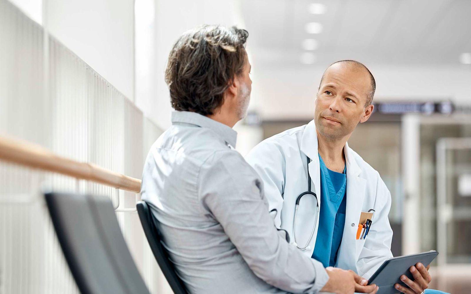 Bauchspeicheldrüsenkrebs: Arzt spricht mit Mann im Krankenhaus.