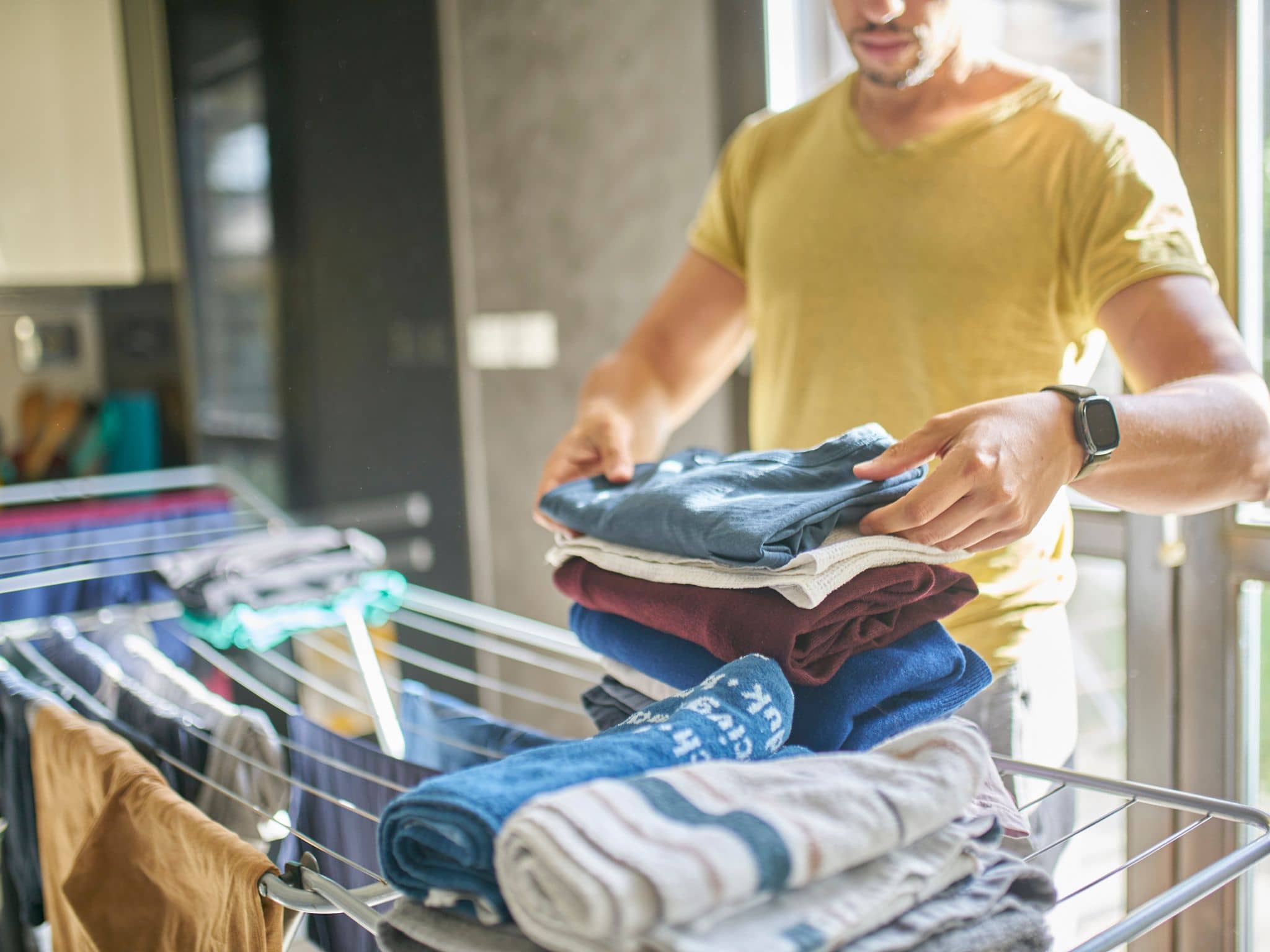 Wie oft Wäsche waschen? Mann nimmt getrocknete Wäsche ab.