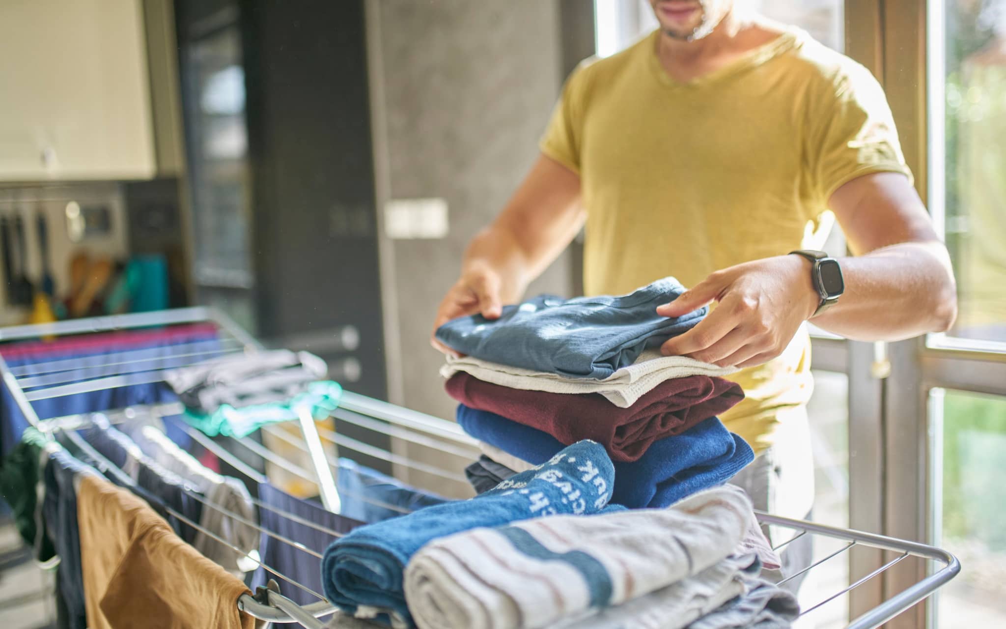 Wie oft Wäsche waschen? Mann nimmt getrocknete Wäsche ab.