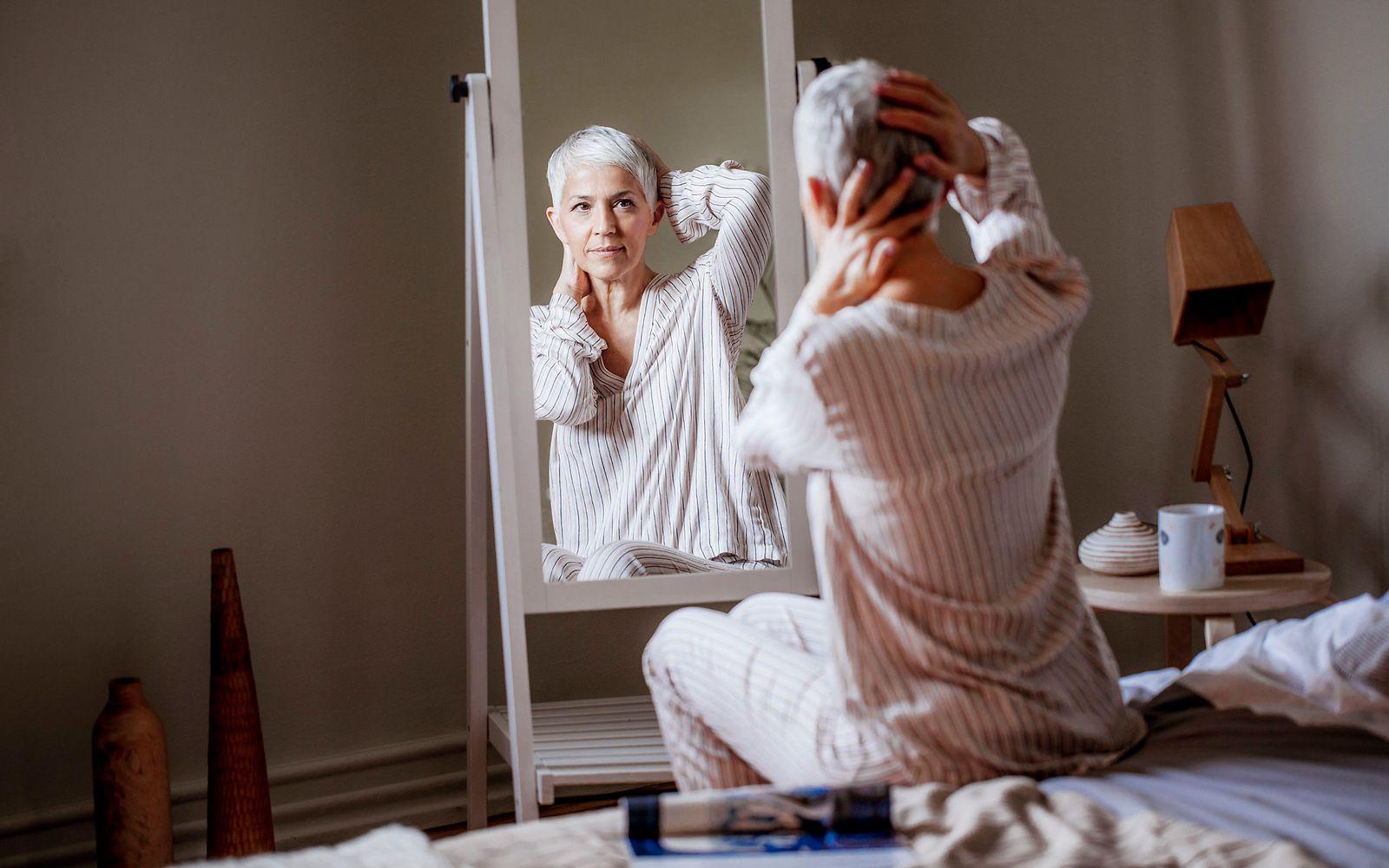 Eierstockkrebs: Ältere Frau betrachtet sich im Spiegel.