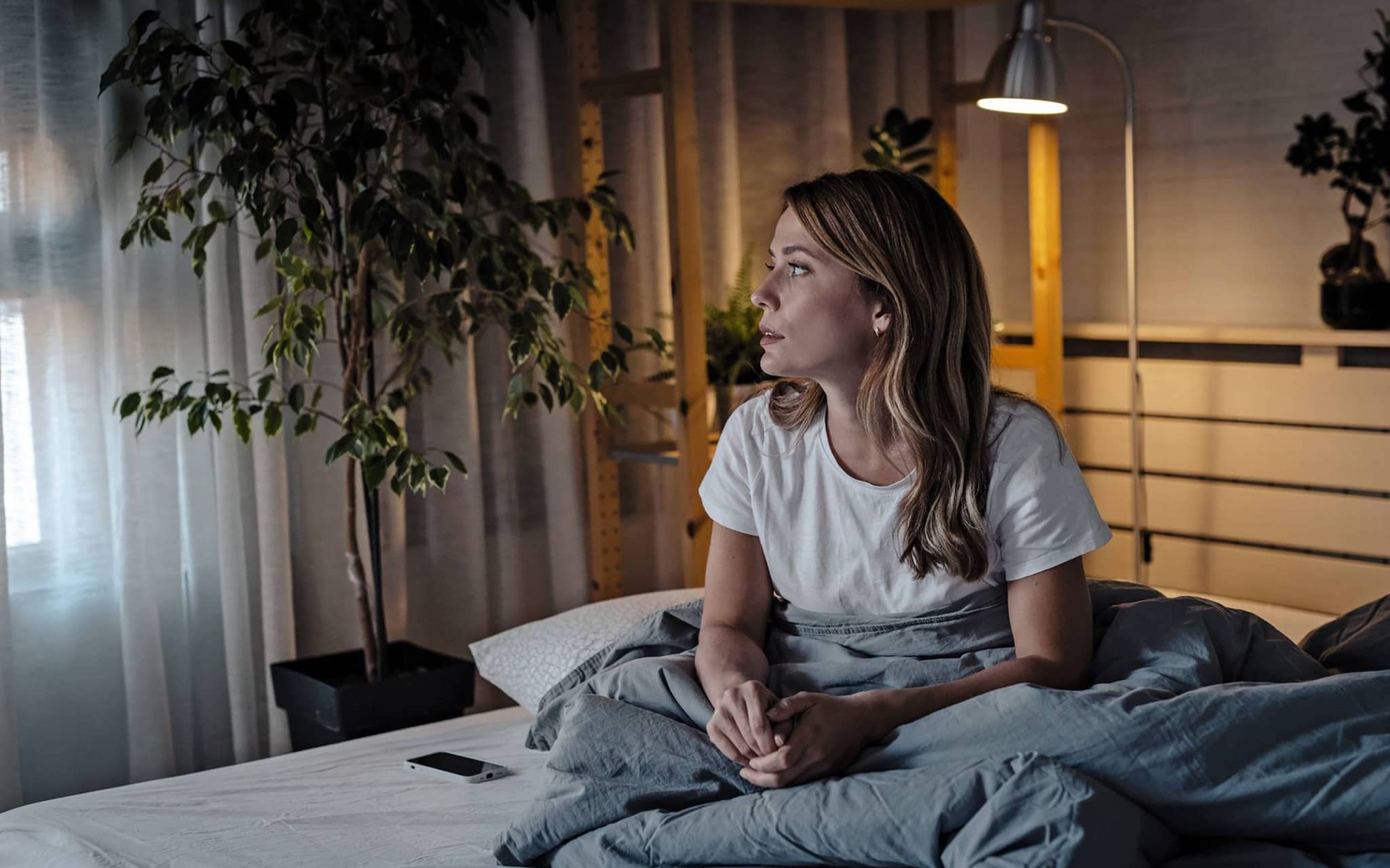 Eine Frau sitzt besorgt auf dem Bett, da sie die Diagnose Gebärmutterhalskrebs bekommen hat.