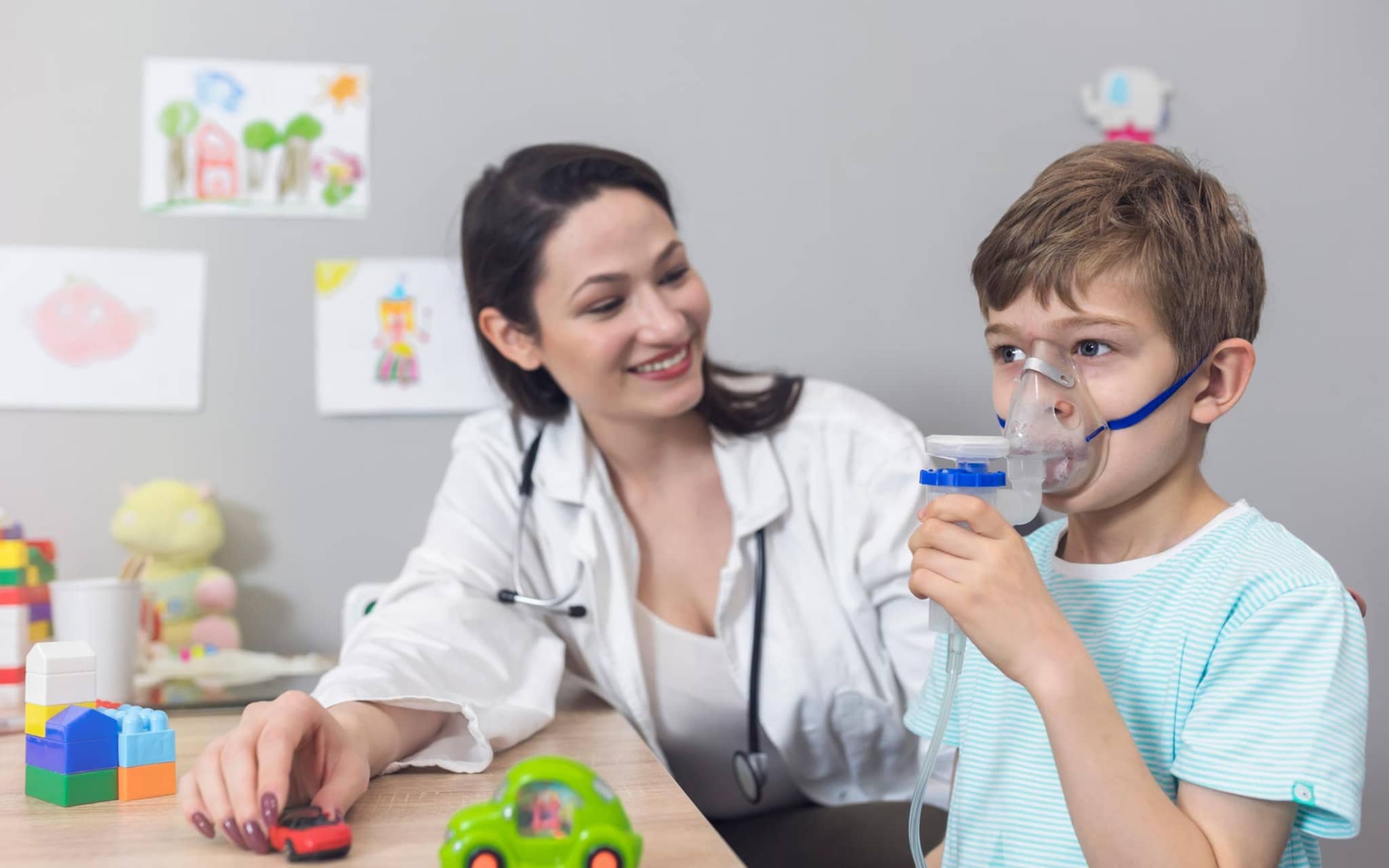 DMP: Ärztin erklärt einem kleinen Jungen die Nutzung eines Asthma-Inhalators.