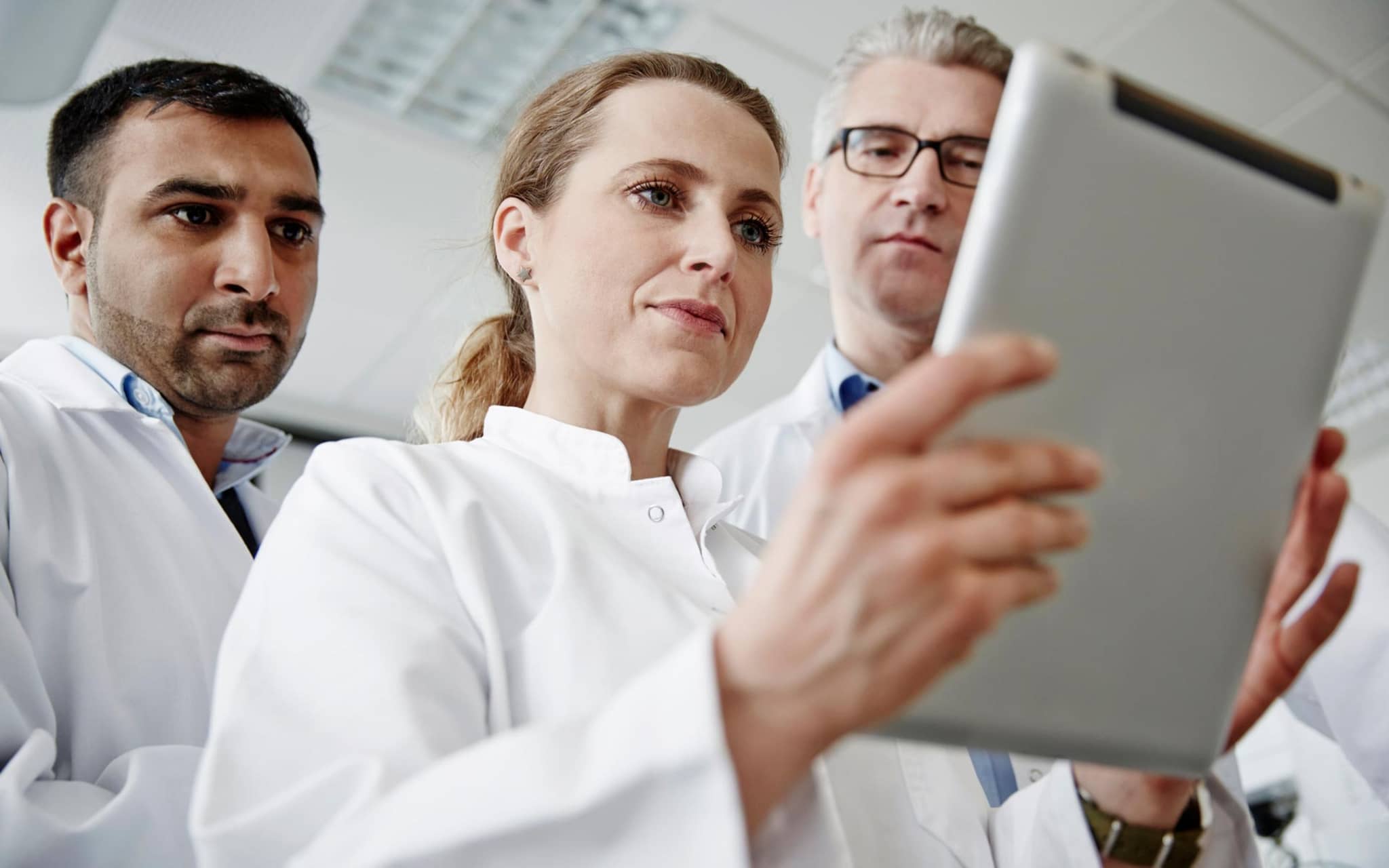 Innovationsfonds: Team von Wissenschaftlern schaut gemeinsam auf ein digitales Tablet.