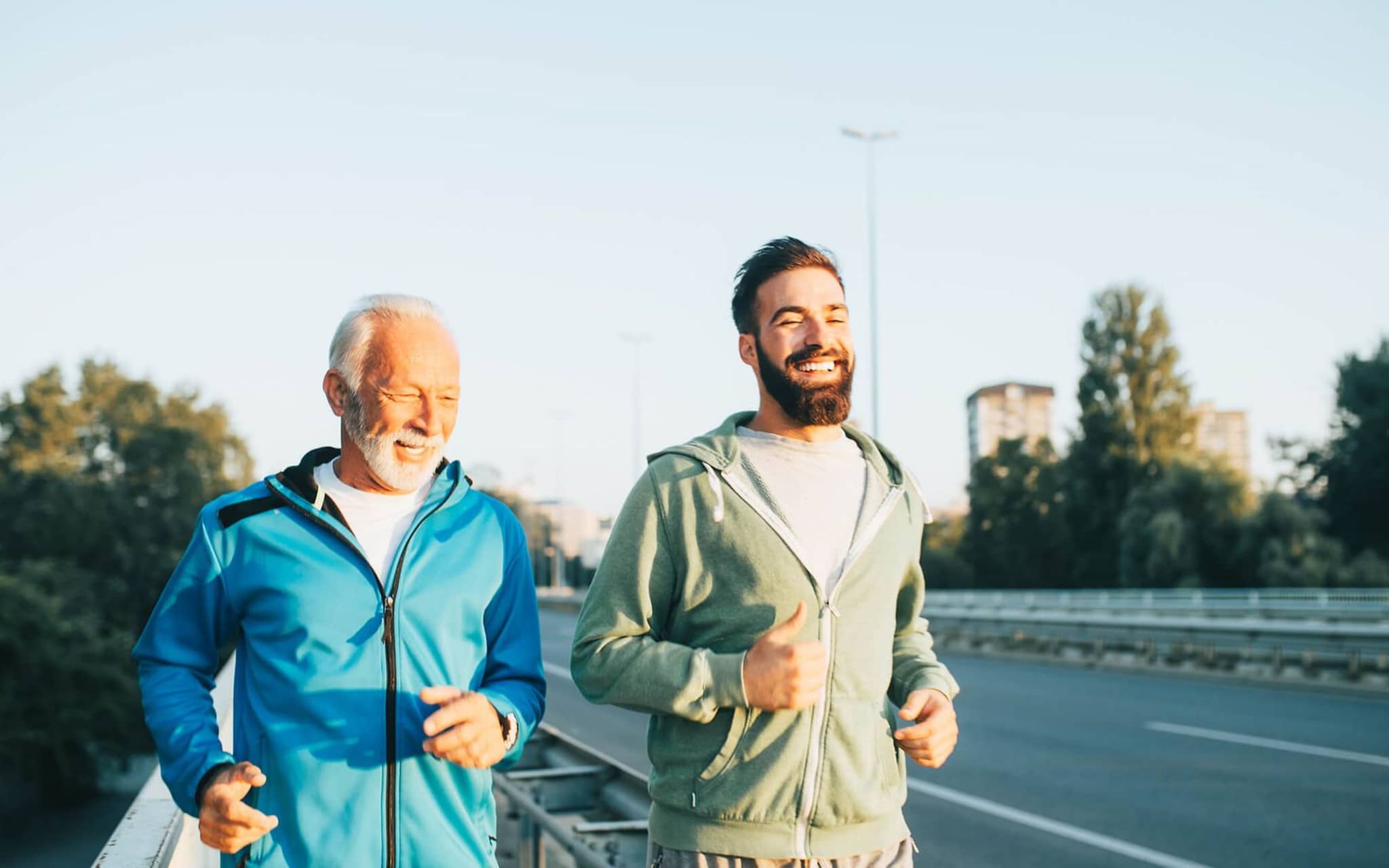 Bewegung und Darmgesundheit: Zwei Männer joggen gemeinsam über eine Brücke.