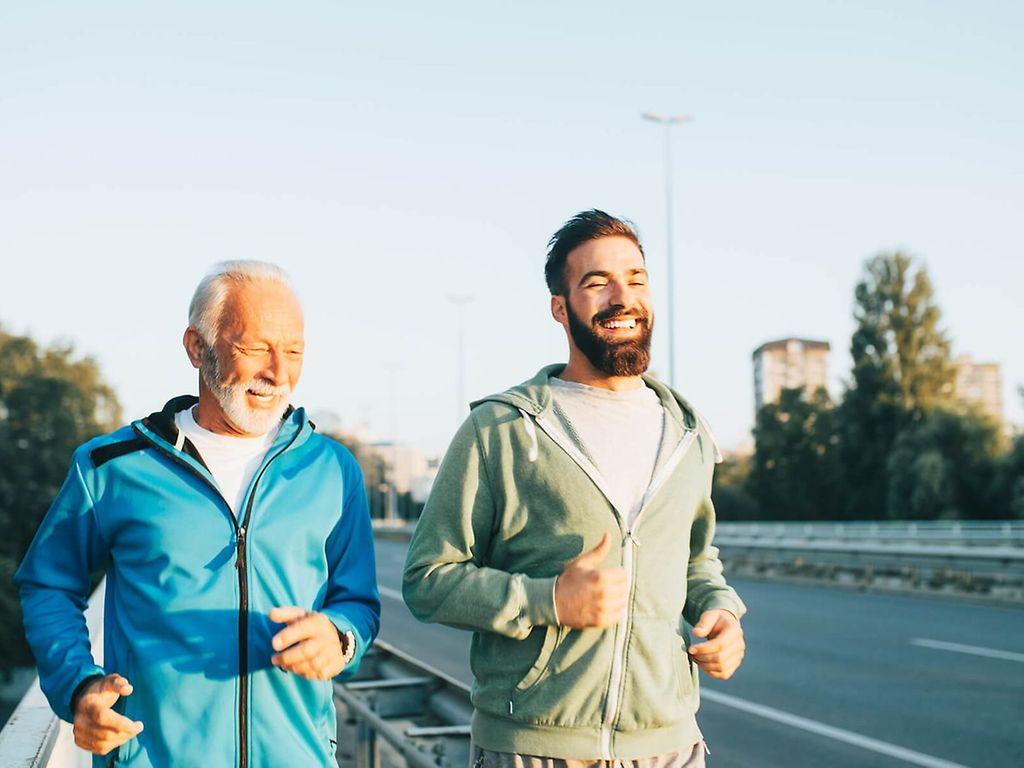 Bewegung und Darmgesundheit: Zwei Männer joggen gemeinsam über eine Brücke.