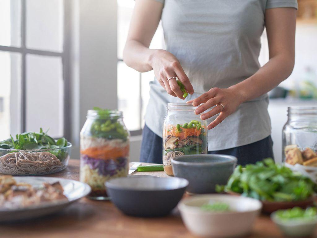 Individuelle Ernährungsberatung: Frauenhände füllen Gemüse in ein Weckglas.