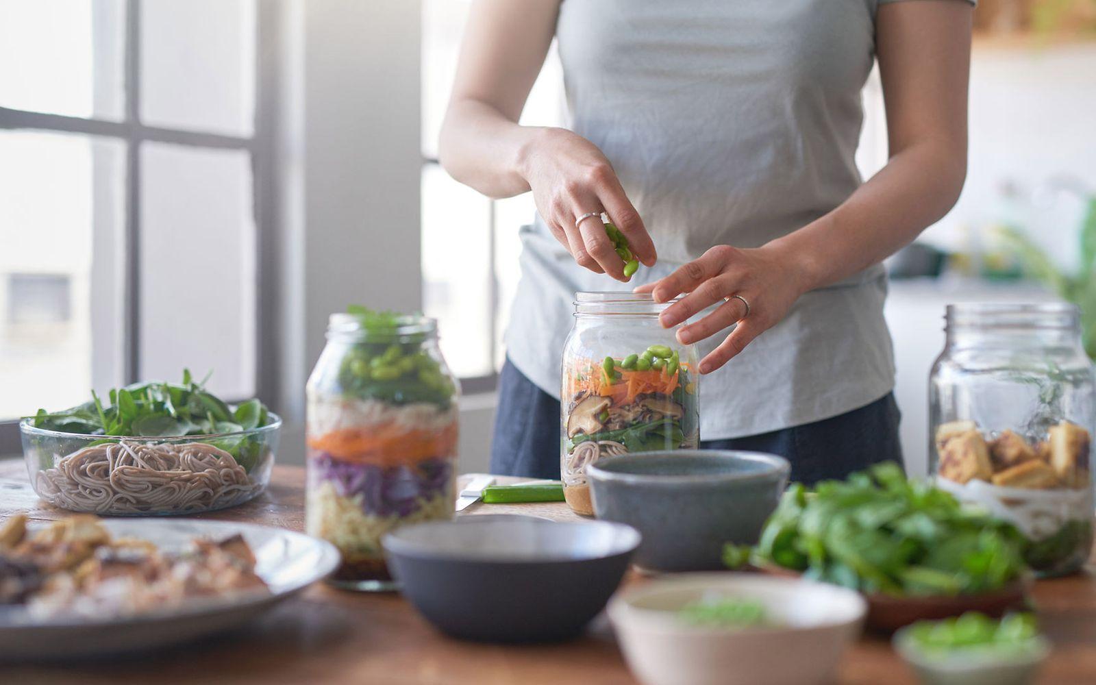 Individuelle Ernährungsberatung: Frauenhände füllen Gemüse in ein Weckglas.