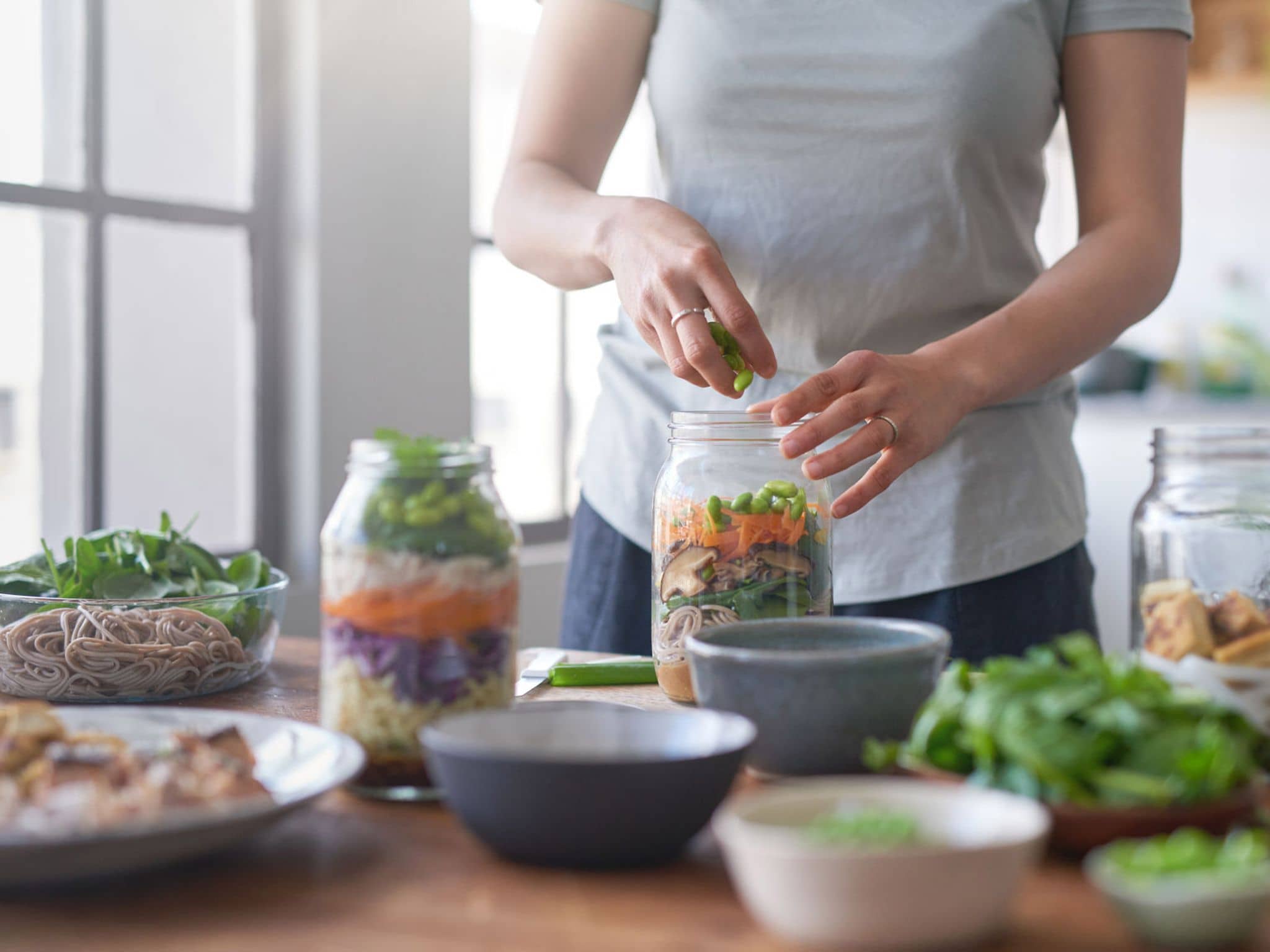 Individuelle Ernährungsberatung: Frauenhände füllen Gemüse in ein Weckglas.