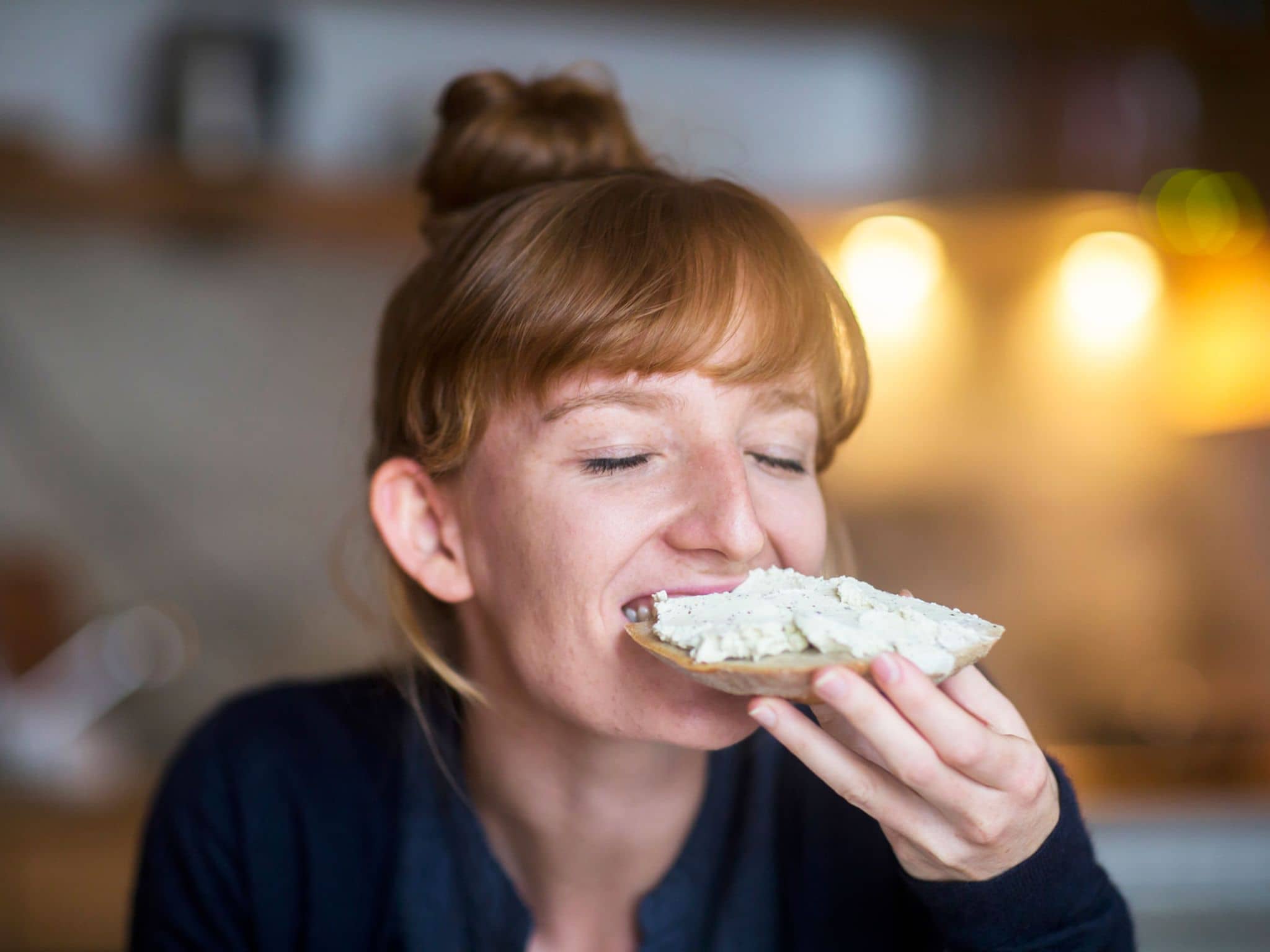 Brotaufstriche: Junge Frau beißt genüsslich in ein Butterbrot.