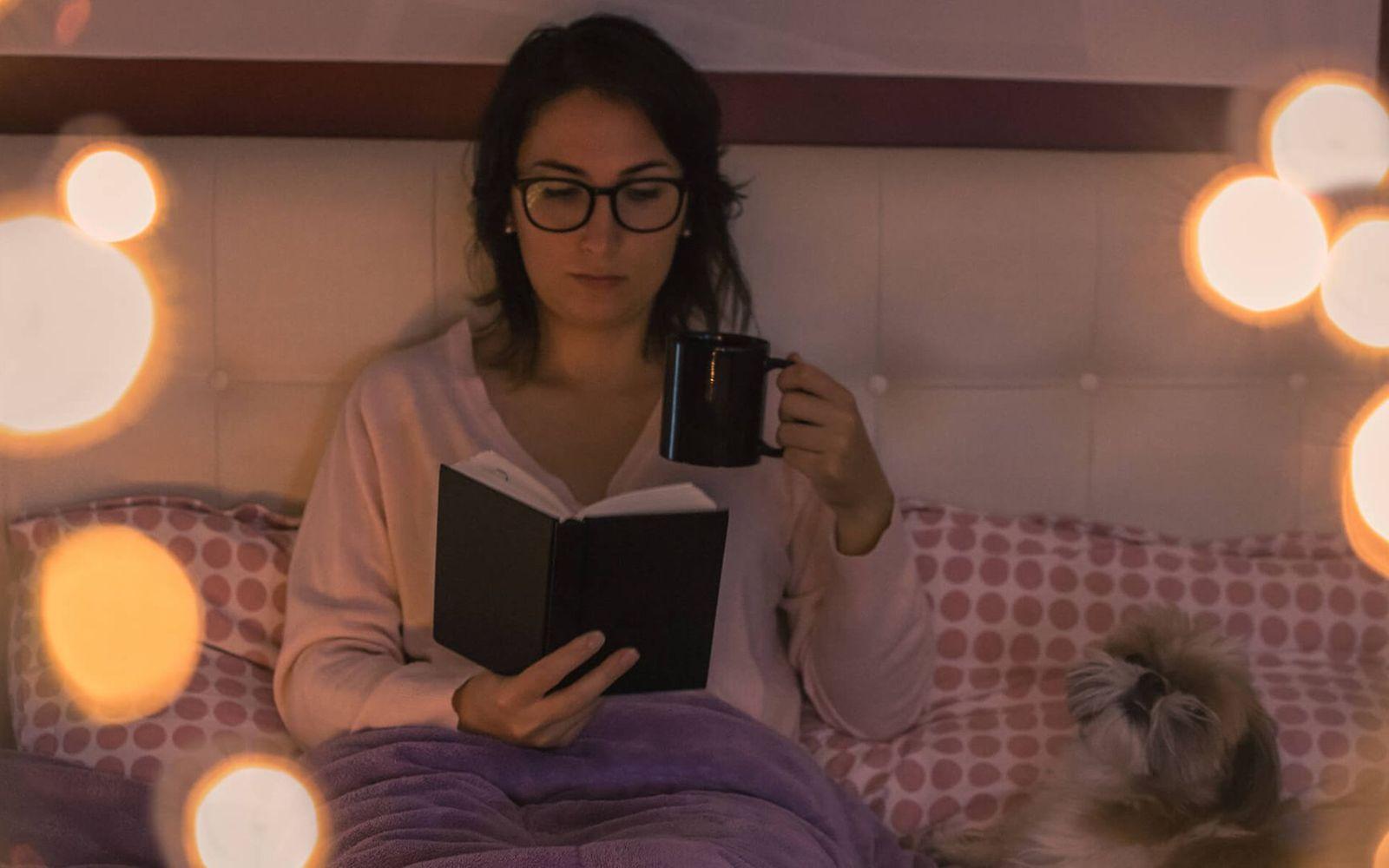 Erholsamer Schlaf: Frau sitzt am Abend auf dem Bett und liest.