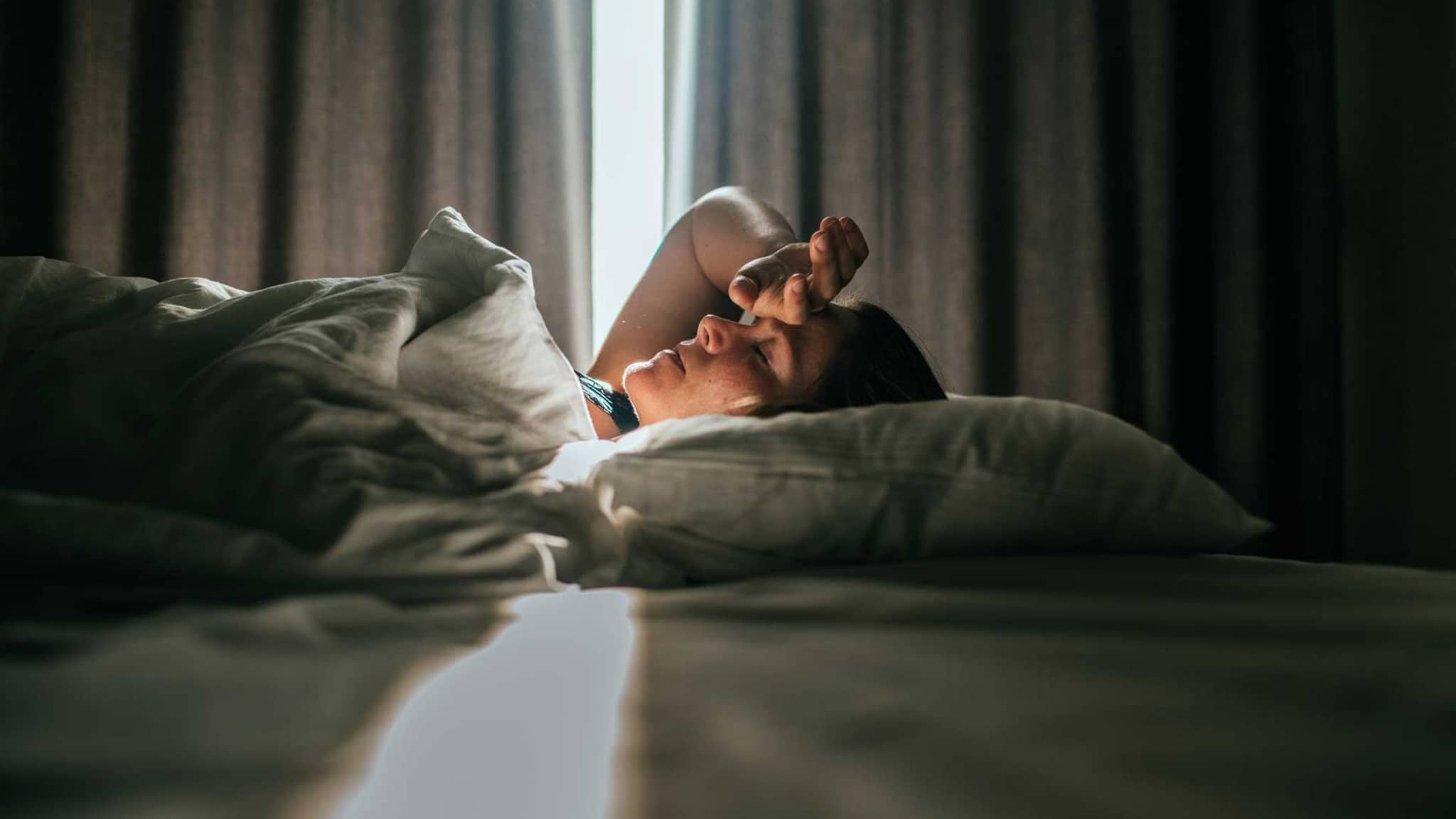 Frau liegt krank in einem Hotelbett