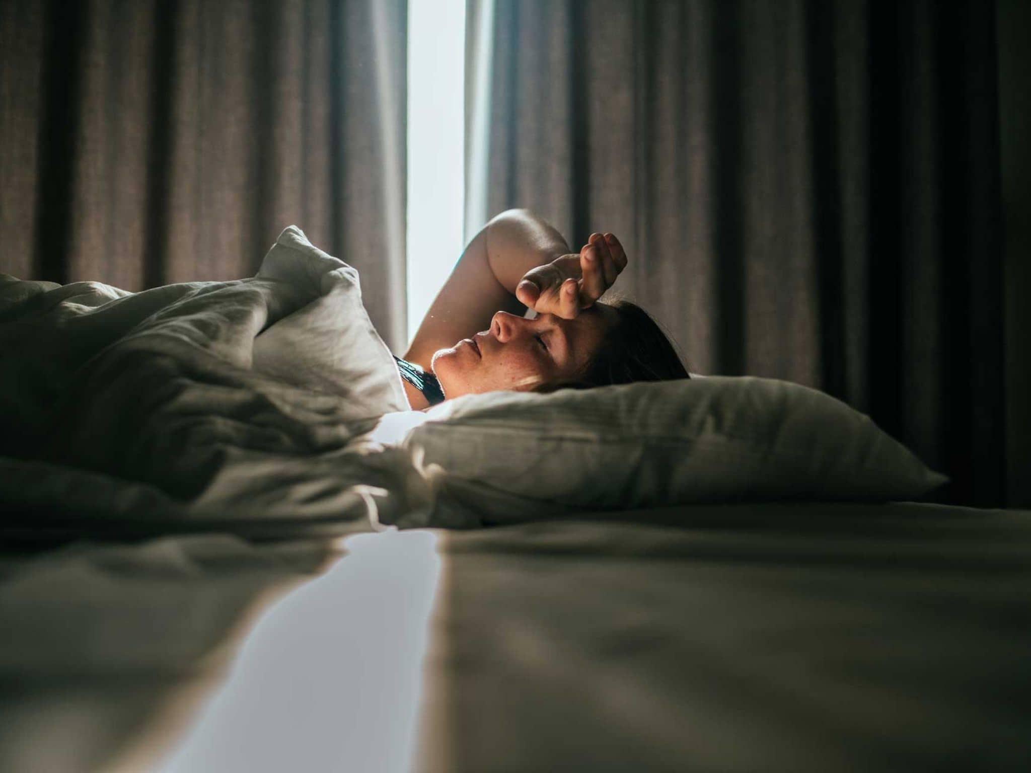 Frau liegt krank in einem Hotelbett