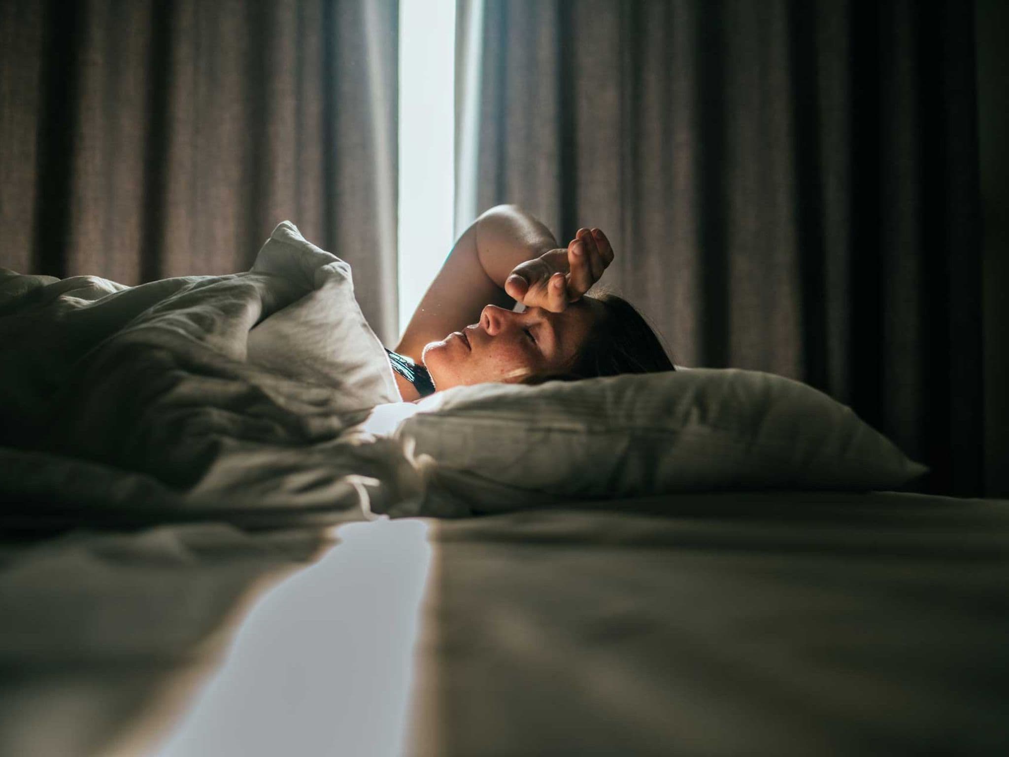 Frau liegt krank in einem Hotelbett