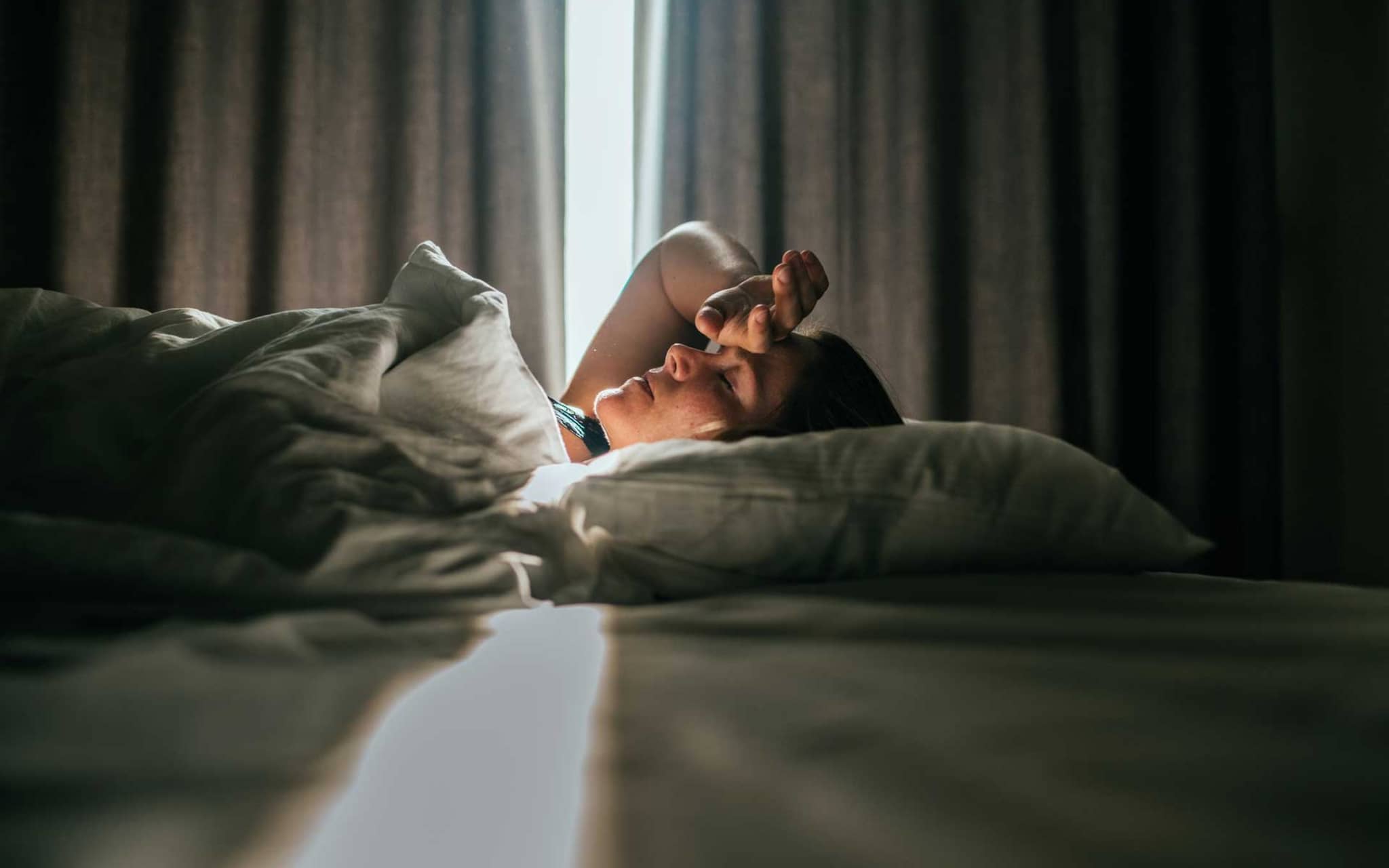 Frau liegt krank in einem Hotelbett