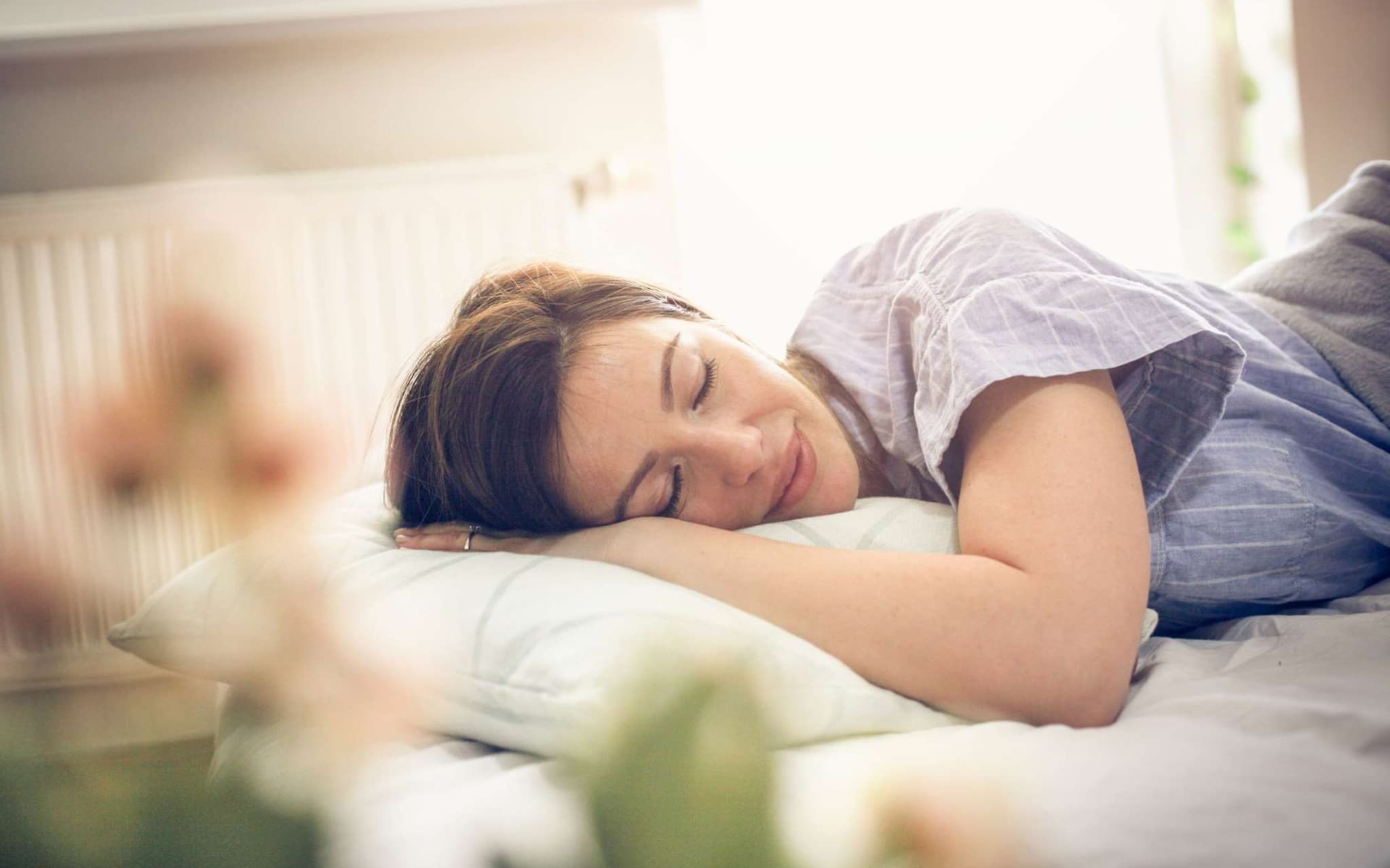 Meditation gegen Schlafstörungen: Frau schläft entspannt in ihrem Bett.