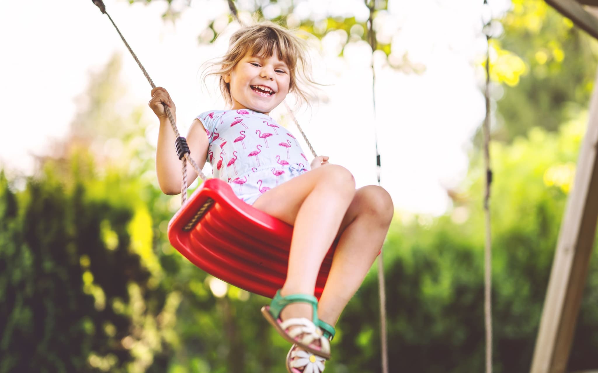 Resilienz bei Kindern: Ein kleines Mädchen schaukelt und lächelt glücklich