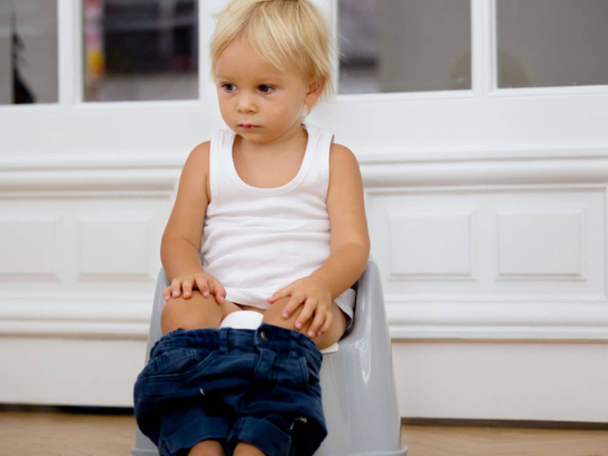 Farbe des Urins: Ein kleiner Junge sitzt auf einem Töpfchen und macht Pipi
