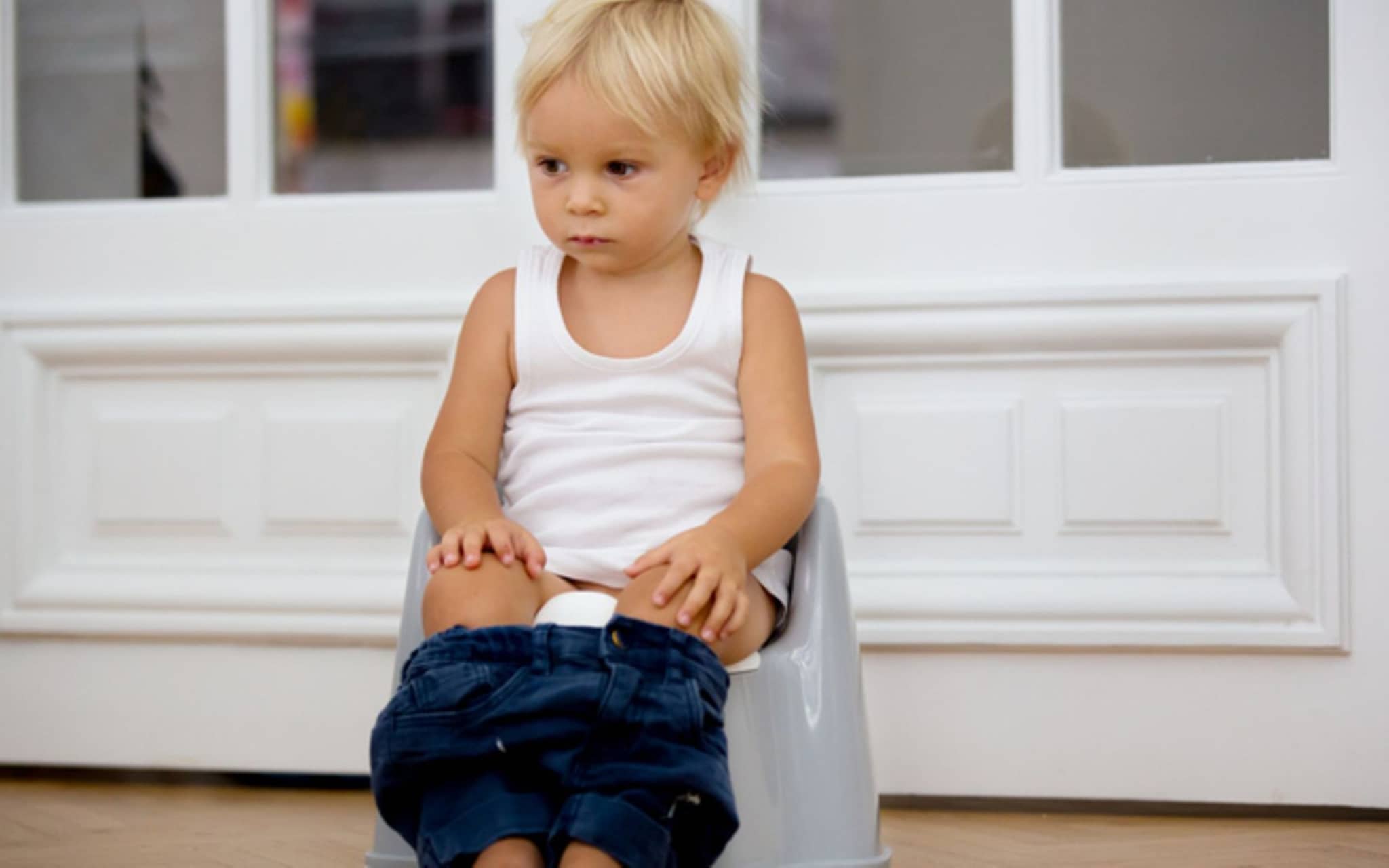 Ein kleiner Junge sitzt auf einem Töpfchen und macht Pipi